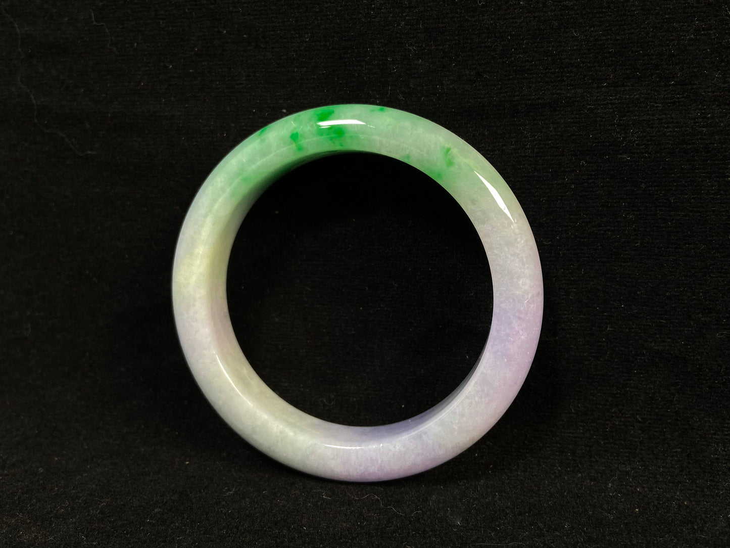 This natural jadeite bangle features a white base, elegantly divided into three sections: one in purple, one in green, and one in white with a subtle yellowish hue.