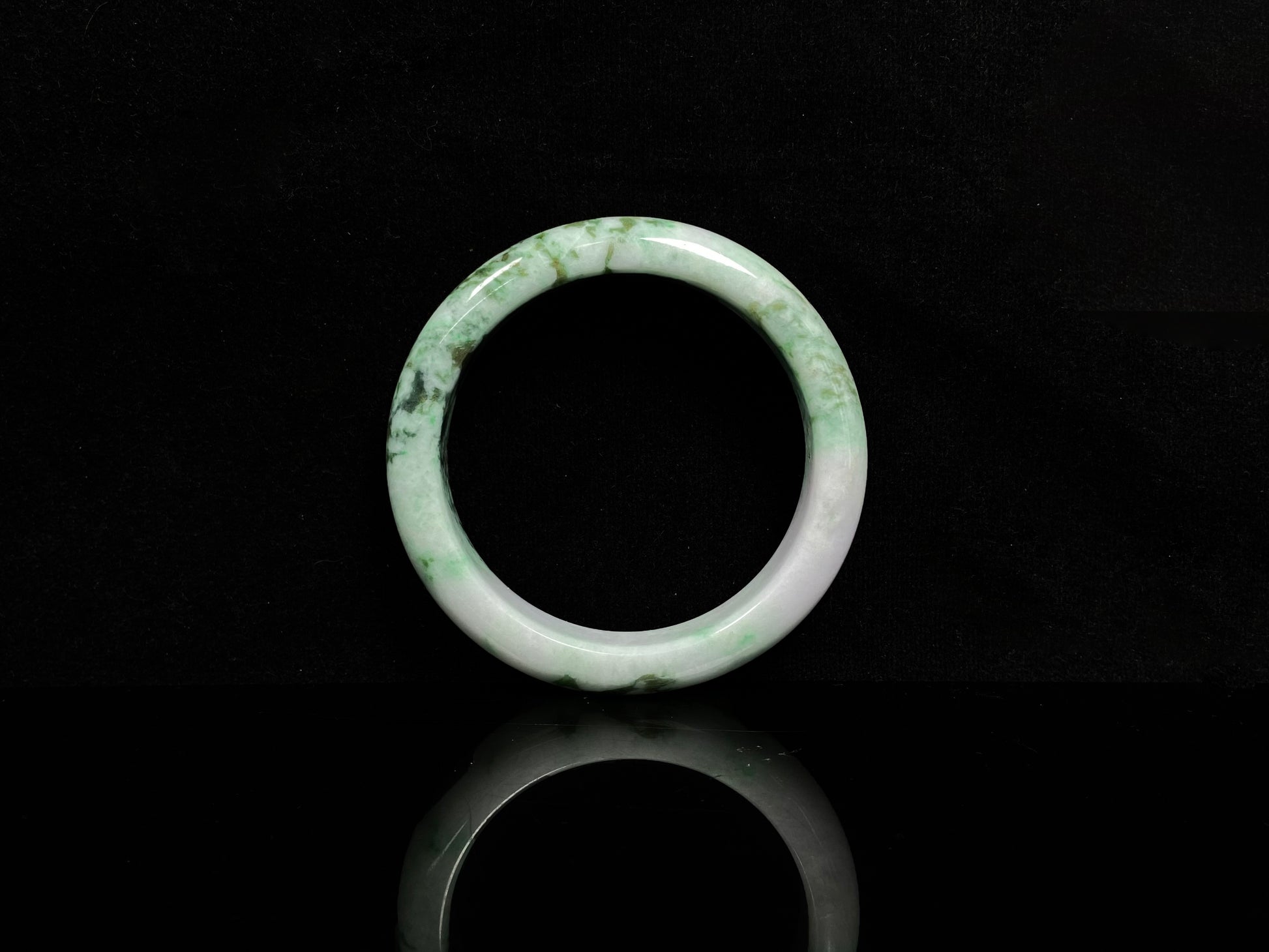 A white base with mottled green textures jadeite bangle.