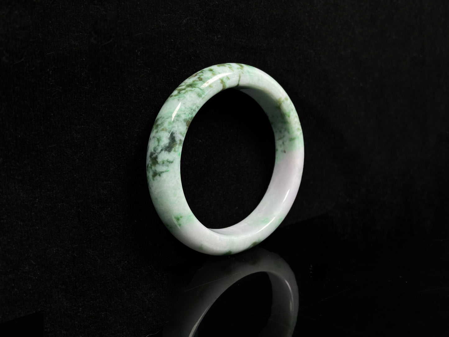A white base with mottled green textures jadeite bangle.