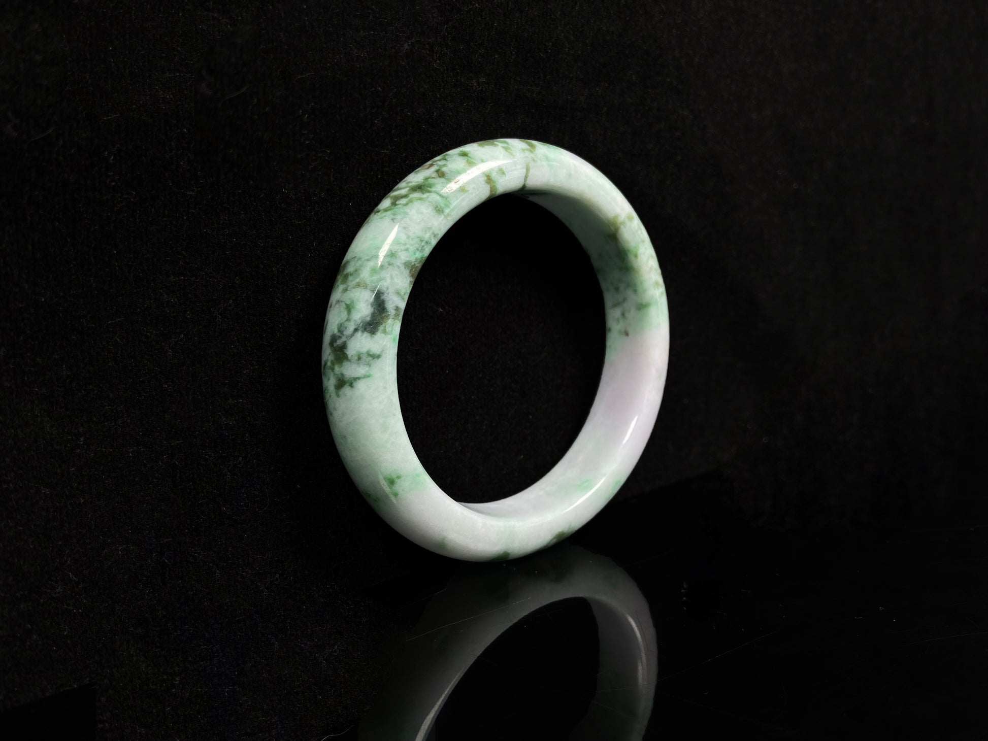 A white base with mottled green textures jadeite bangle.