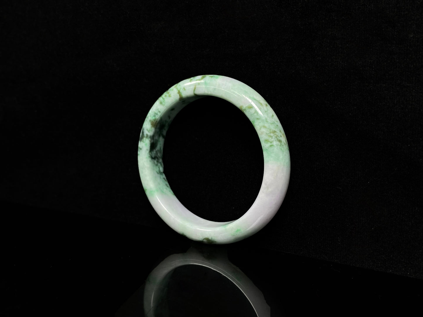 A white base with mottled green textures jadeite bangle.