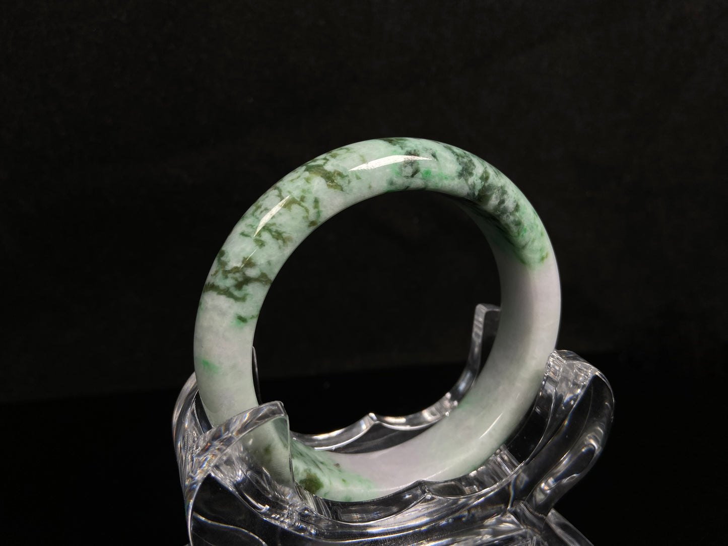 A white base with mottled green textures jadeite bangle.