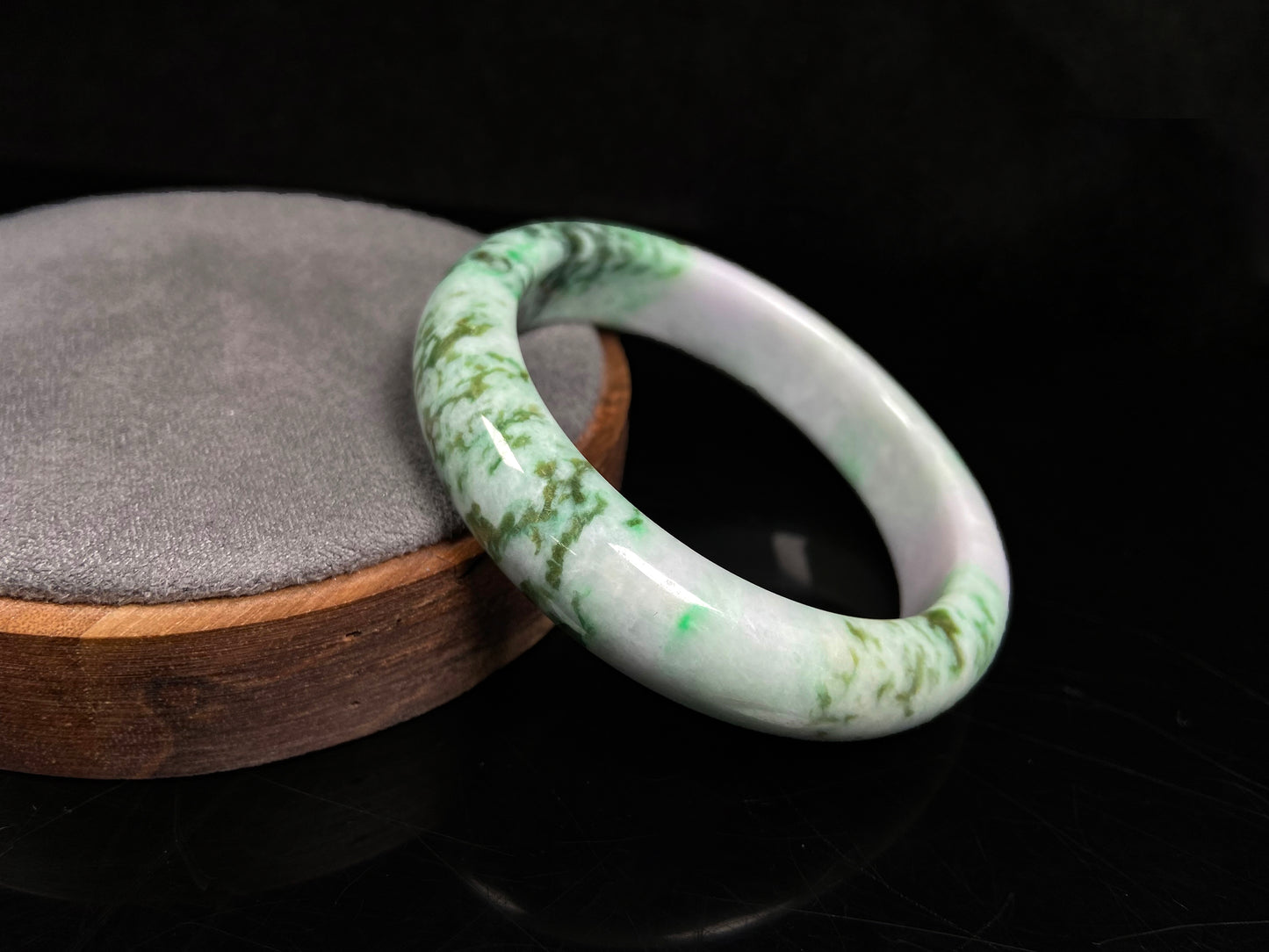 A white base with mottled green textures jadeite bangle.