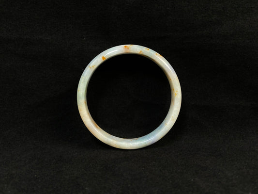 A white jade bracelet adorned with golden speckles and deep green flashes.