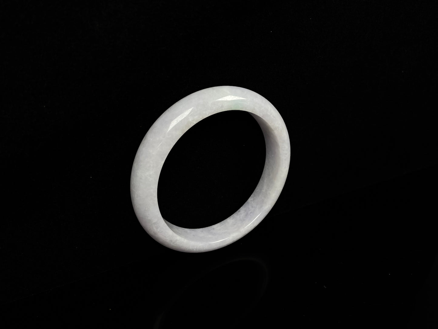 A cloudy white with pale green streaks jadeite bangle.