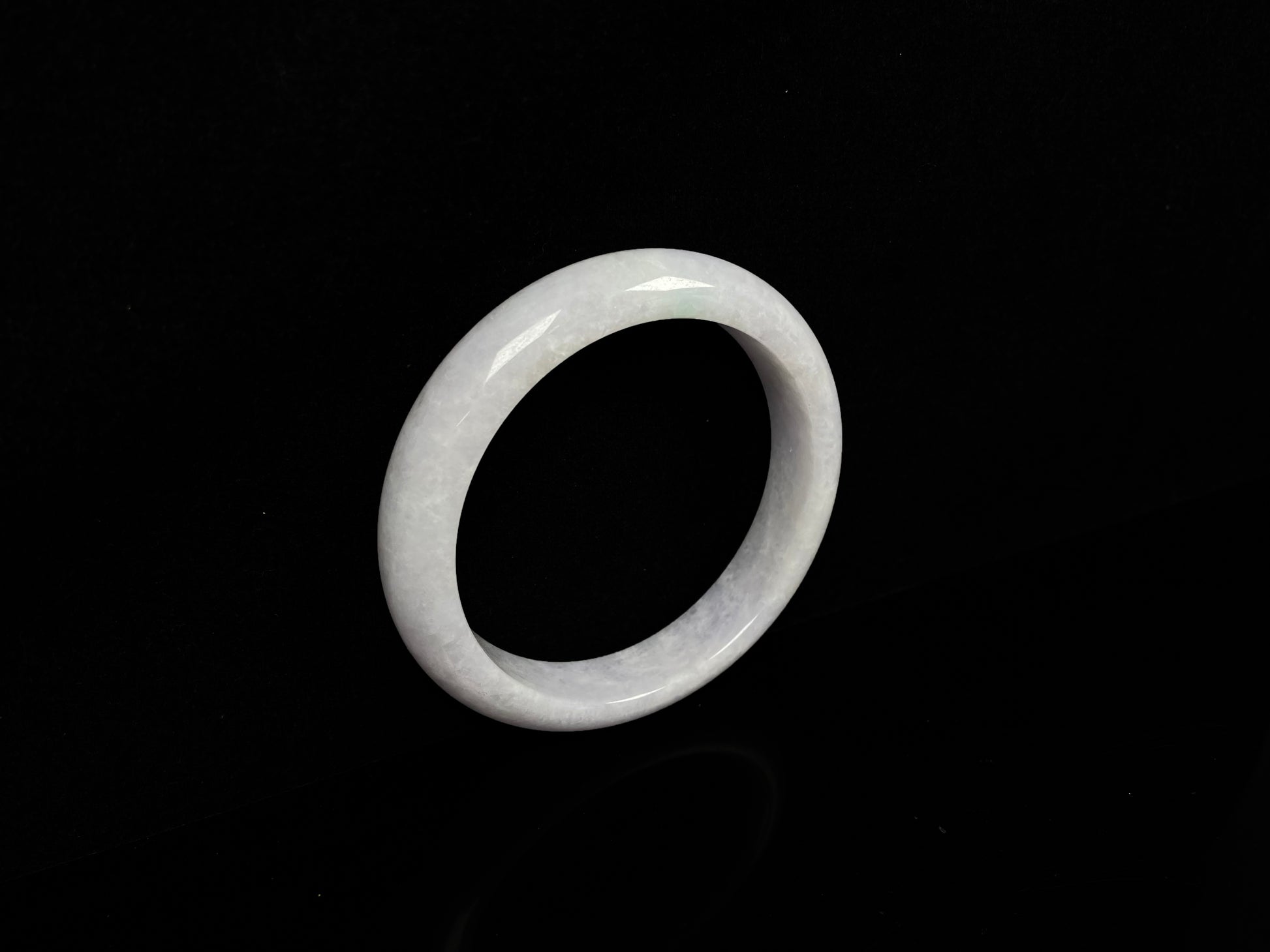 A cloudy white with pale green streaks jadeite bangle.