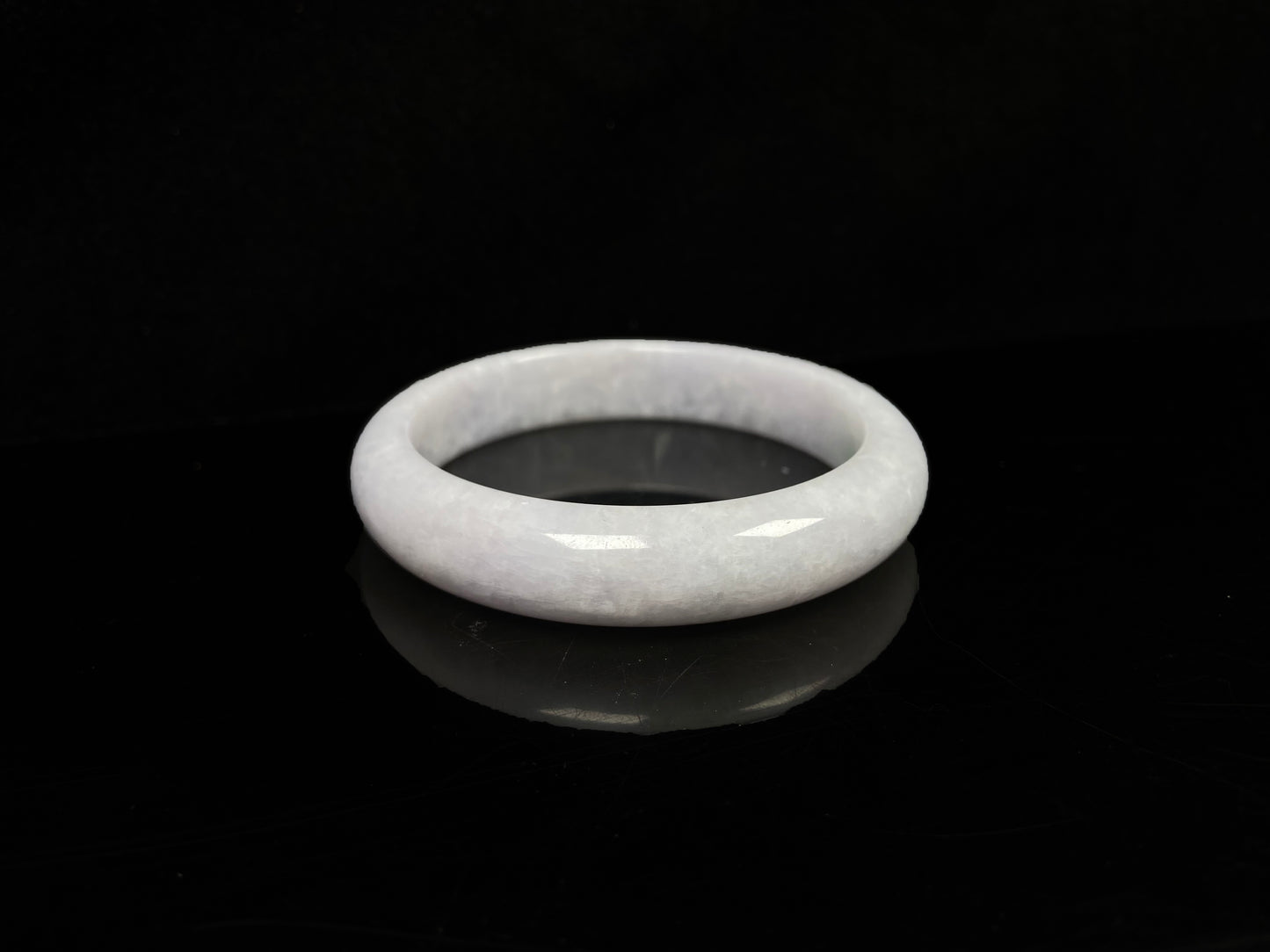 A cloudy white with pale green streaks jadeite bangle.