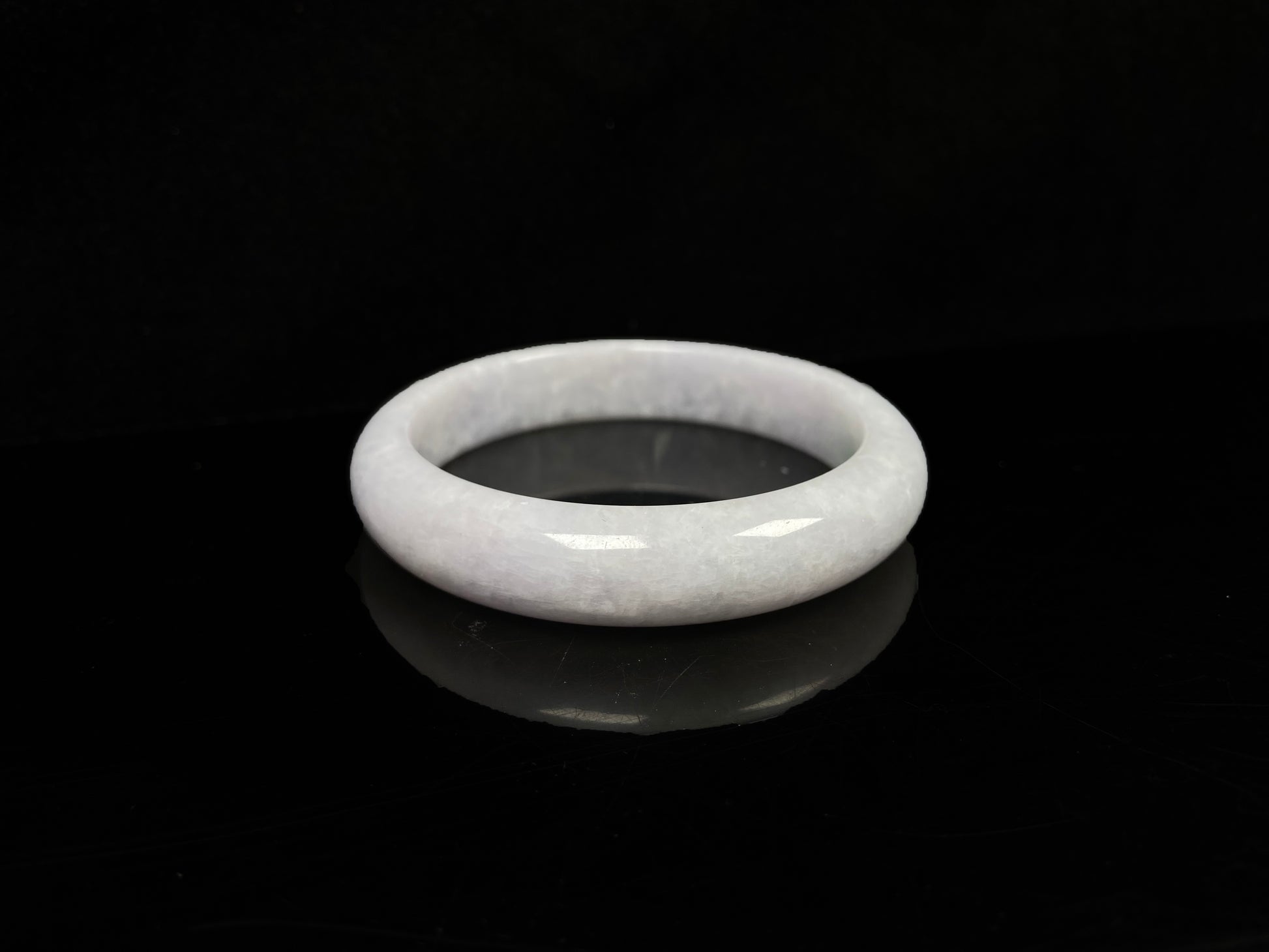 A cloudy white with pale green streaks jadeite bangle.