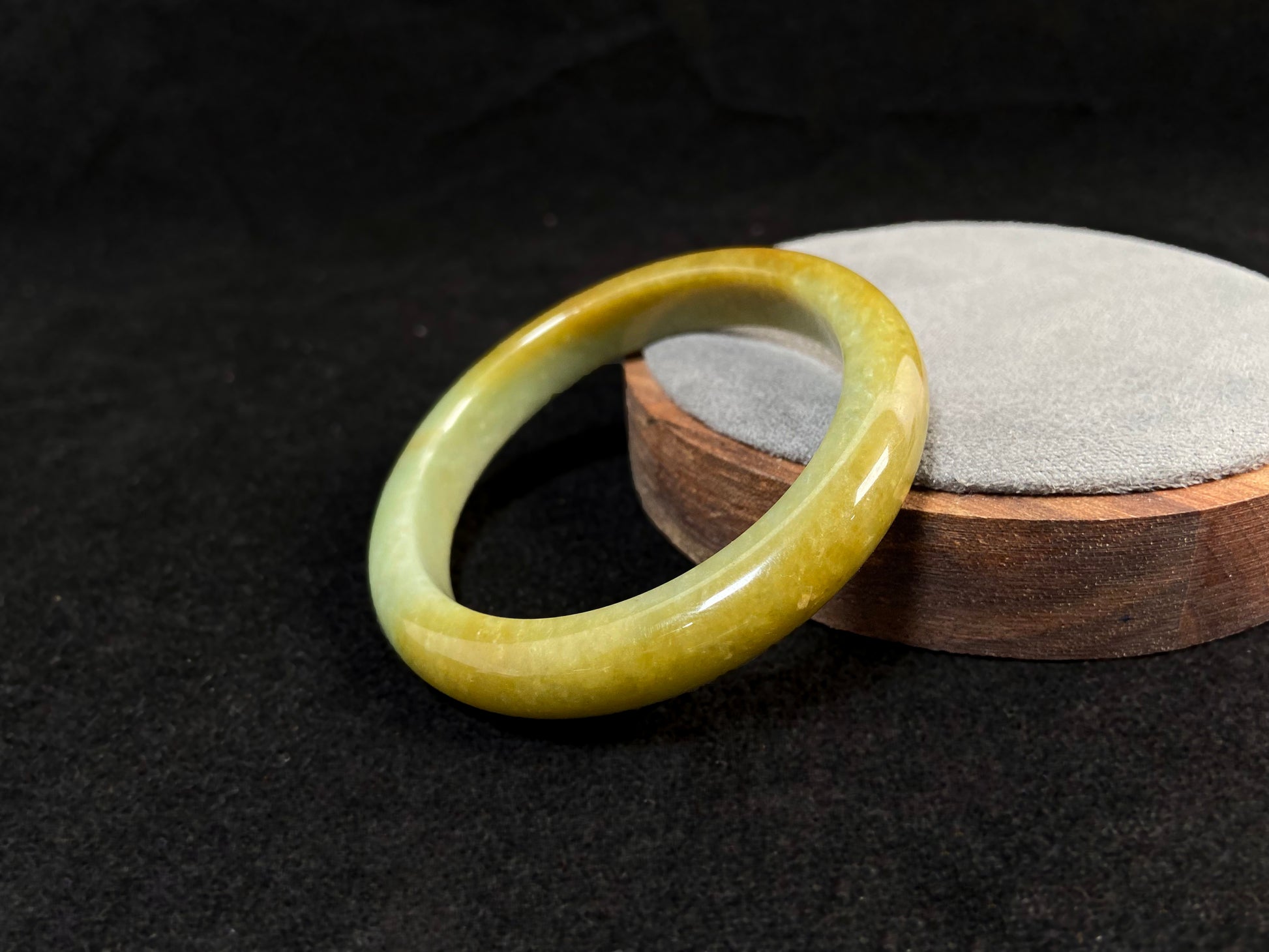 A white and green jade bracelet bathed in golden shimmer.