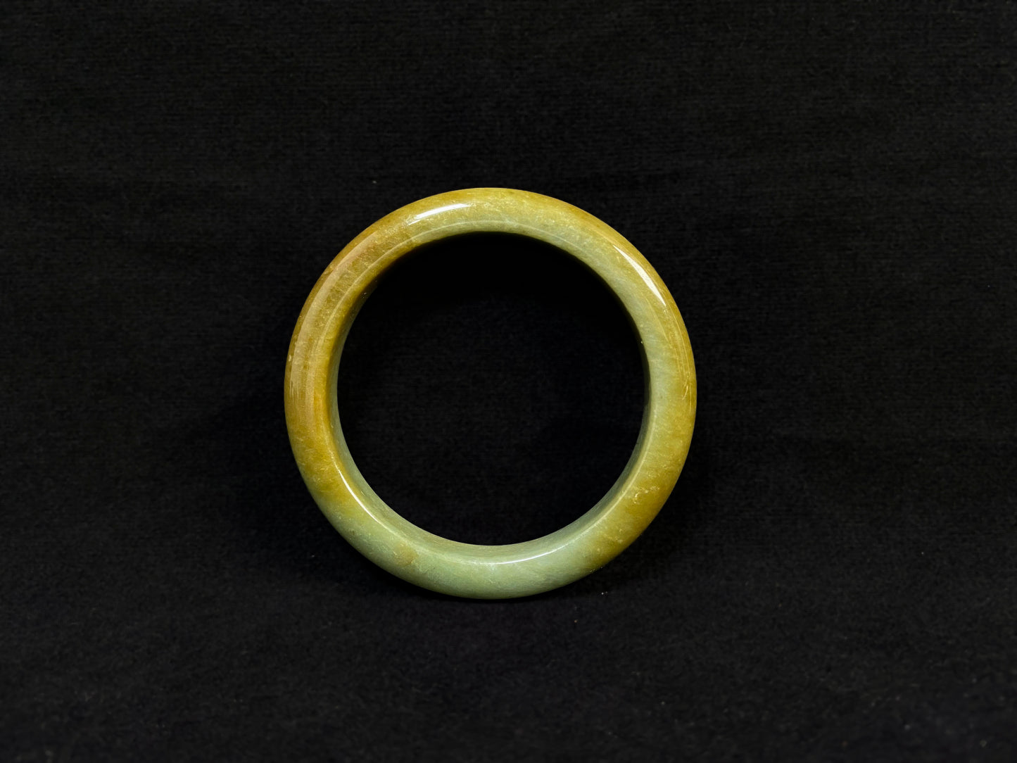 A white and green jade bracelet bathed in golden shimmer.