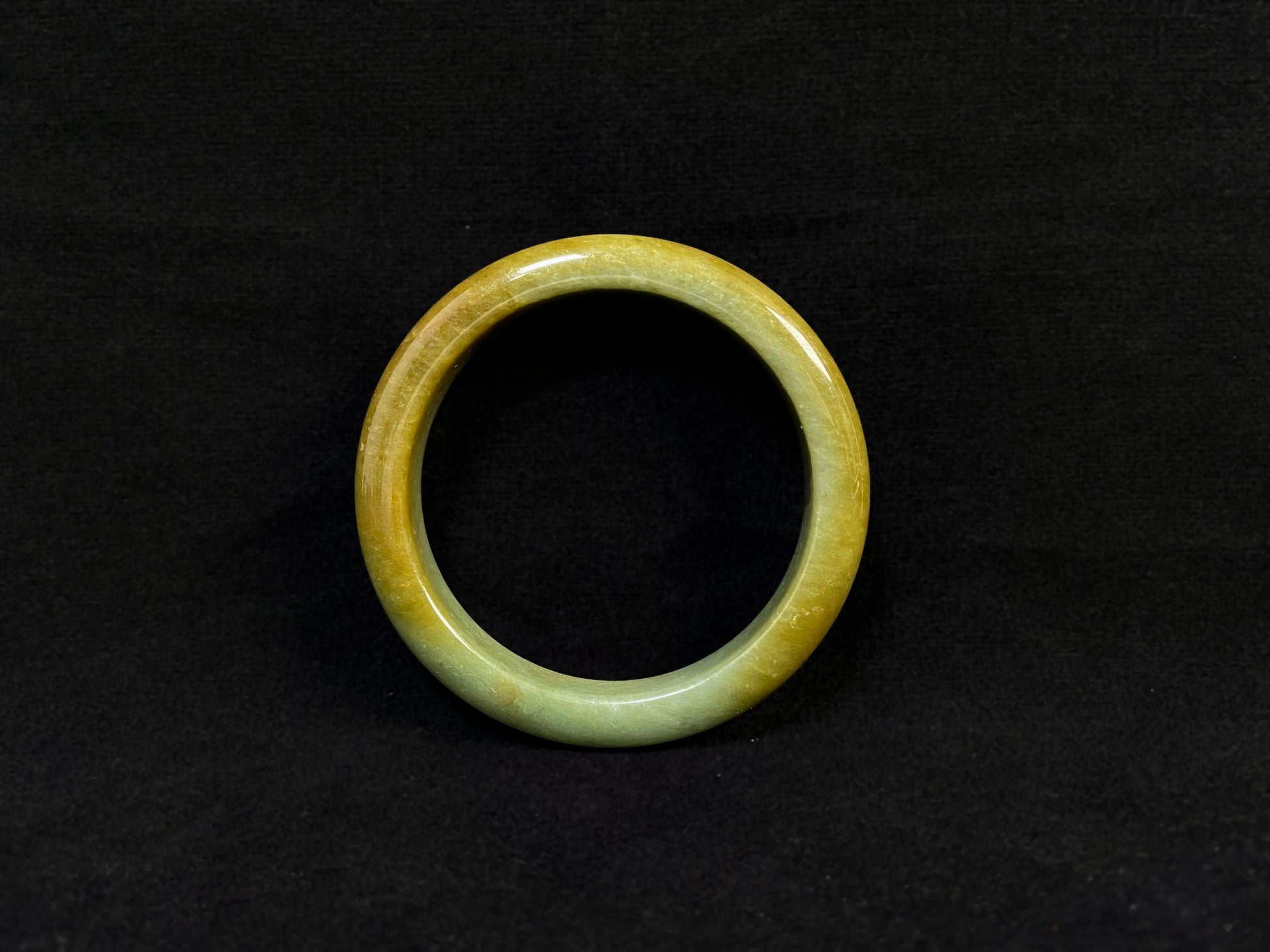 A white and green jade bracelet bathed in golden shimmer.