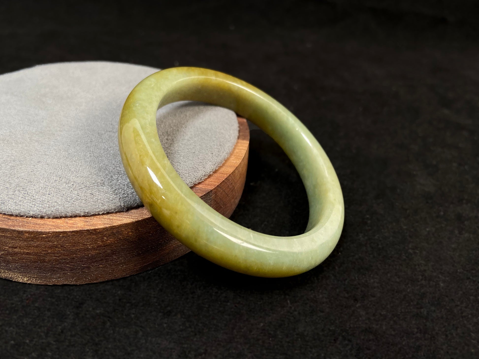 A white and green jade bracelet bathed in golden shimmer.