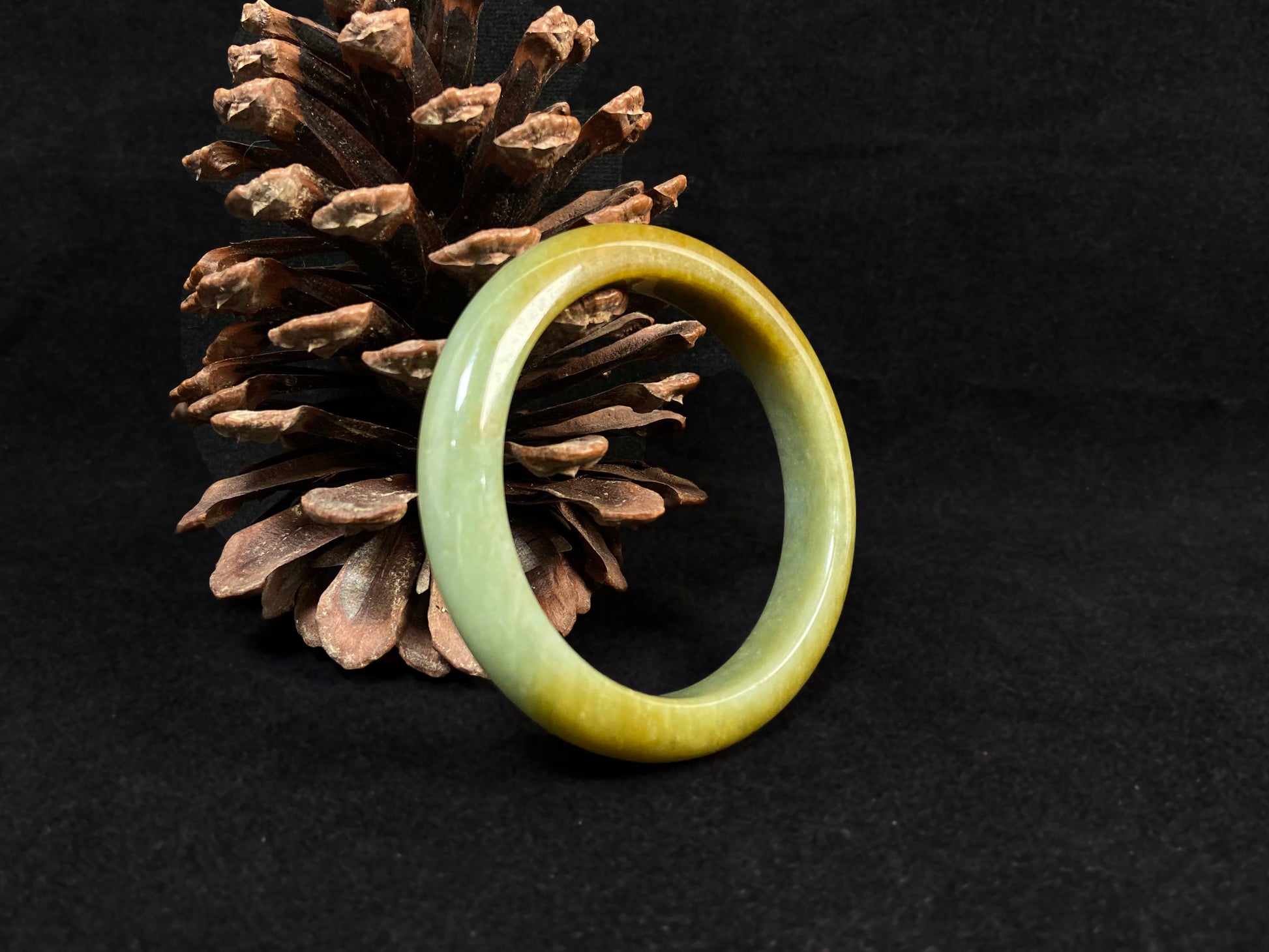A white and green jade bracelet bathed in golden shimmer.