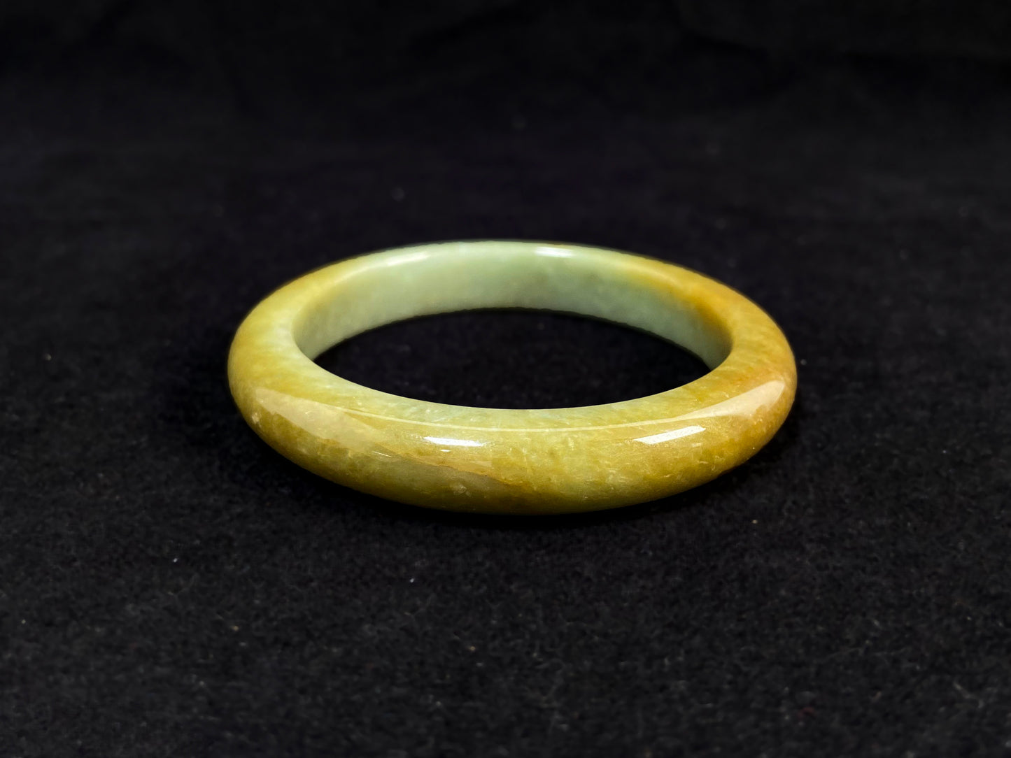 A white and green jade bracelet bathed in golden shimmer.