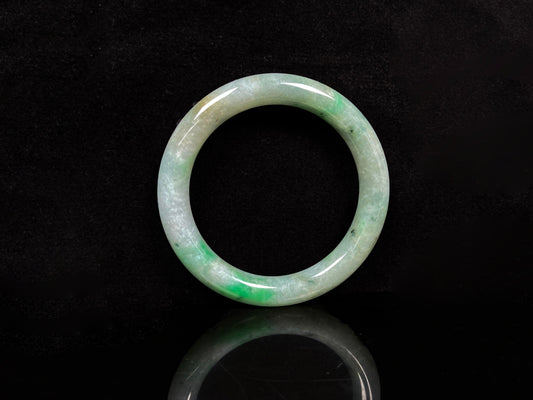 A pale white cyan base with lively green accents  jadeite bangle.