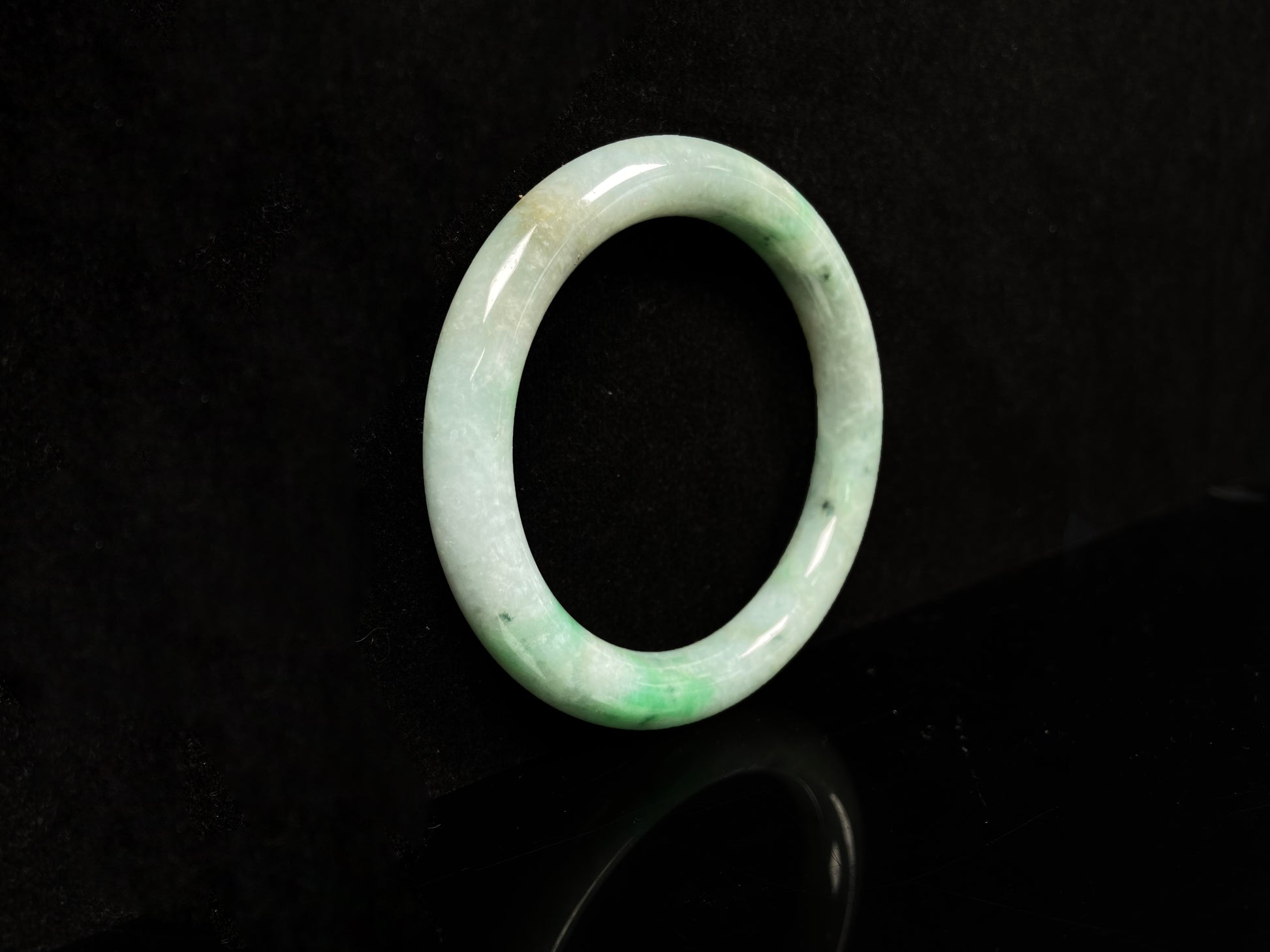 A pale white cyan base with lively green accents  jadeite bangle.