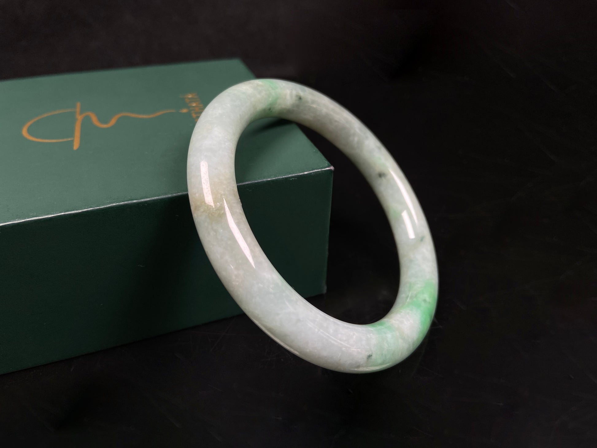 A pale white cyan base with lively green accents  jadeite bangle.