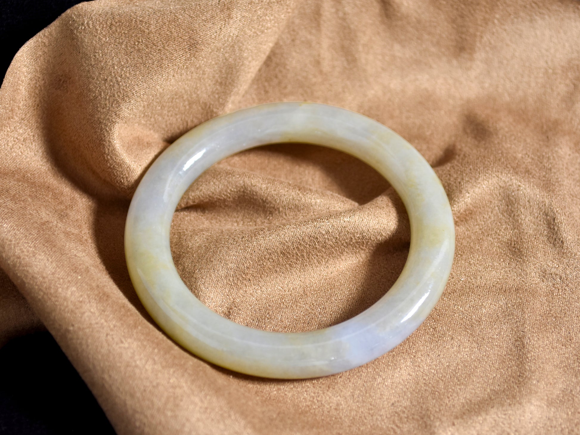 White jade bracelet on a beige fabric background
