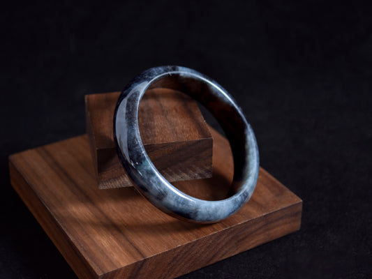 Silver bracelet on a wooden block with a dark background