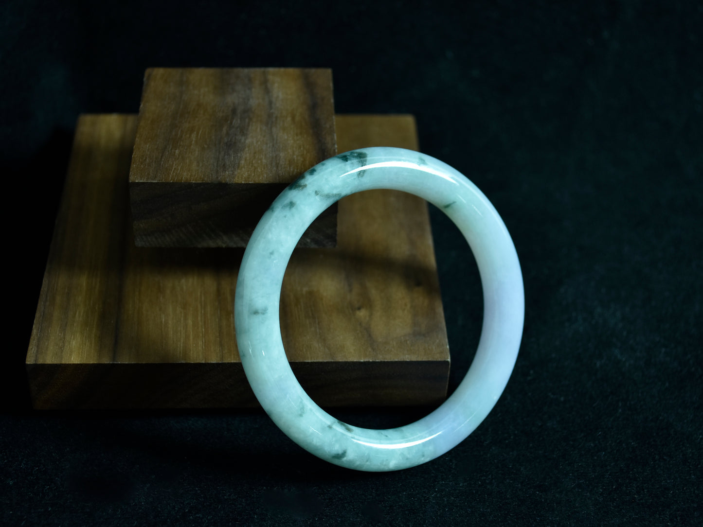 White jade bracelet on a dark surface with wooden blocks