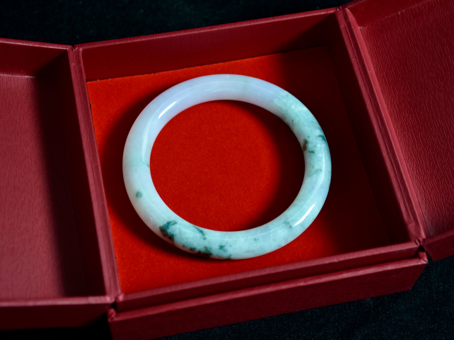 Jade bracelet in a red box on a dark surface