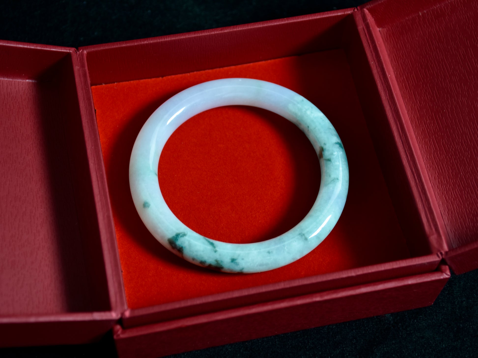 Jade bracelet in a red box on a dark surface
