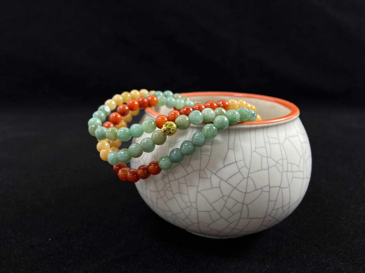 This jade necklace features a repeating pattern of six yellow, six light green, and six orange-red beads, accented with a central golden focal bead.