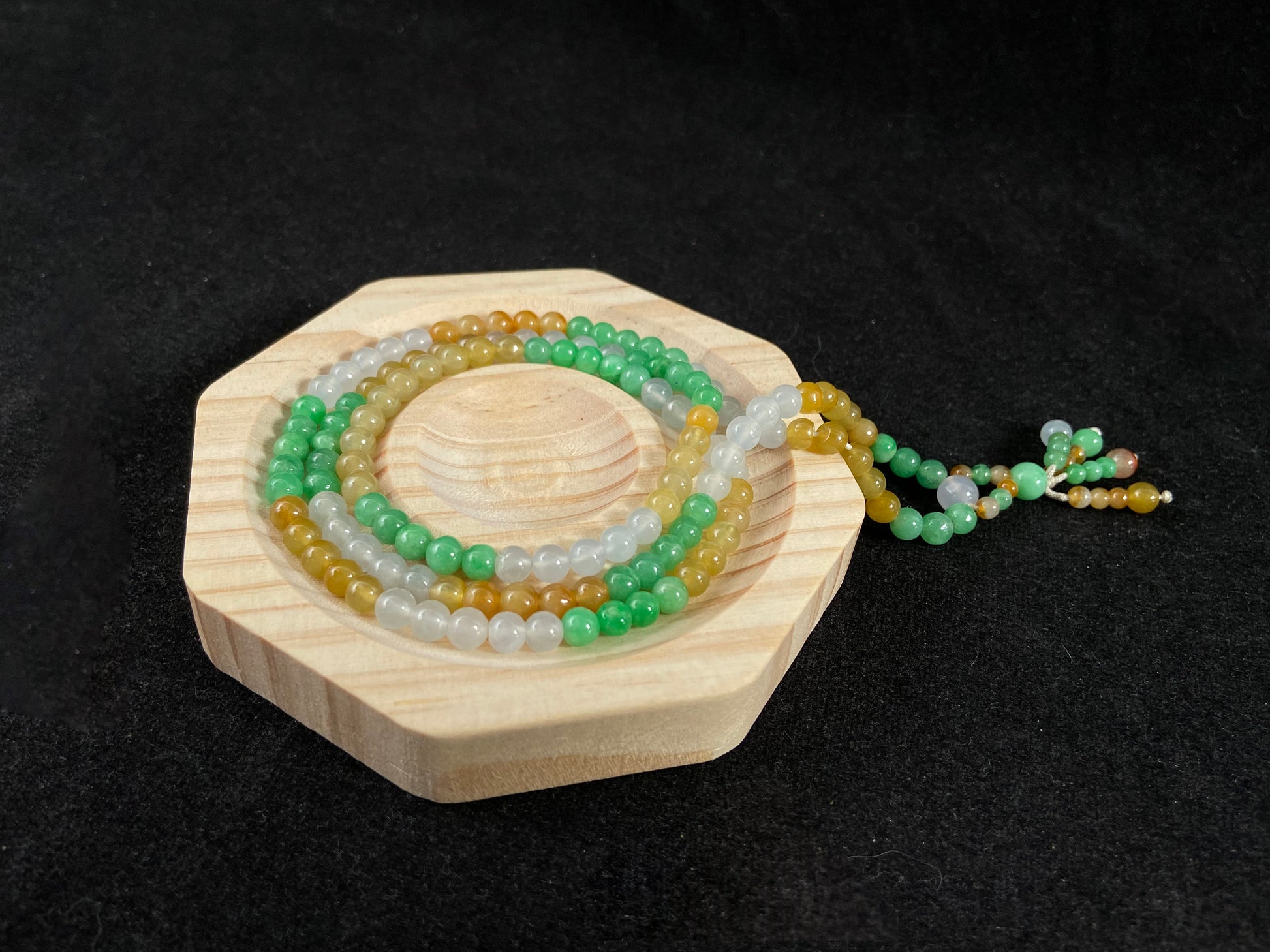 This jade bead strand alternates clusters of apple green, yellow, transparent white, and brown beads in a rhythmic color pattern.