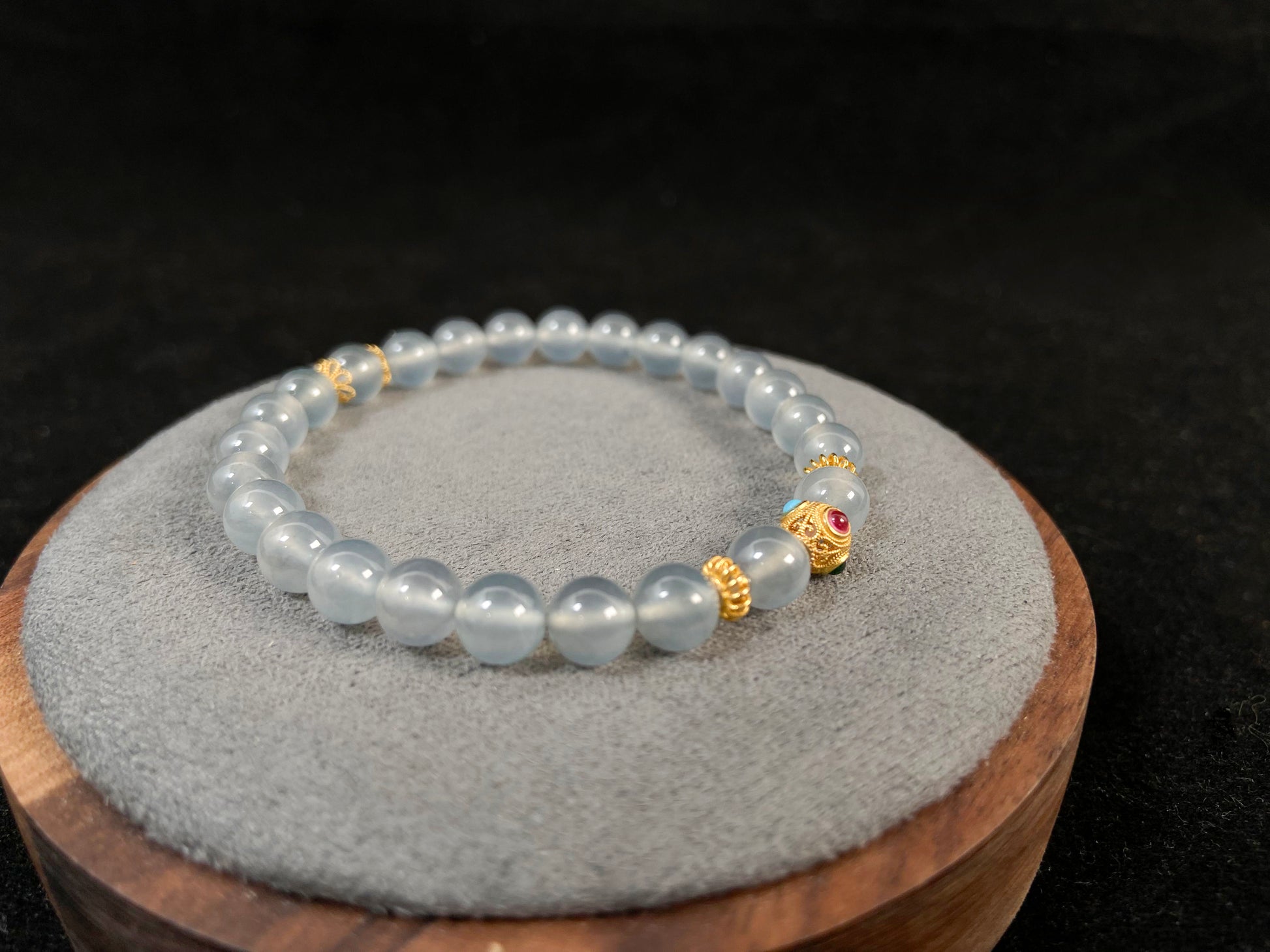 This bracelet combines icy jadeite beads with a hollow 18K gold center bead.