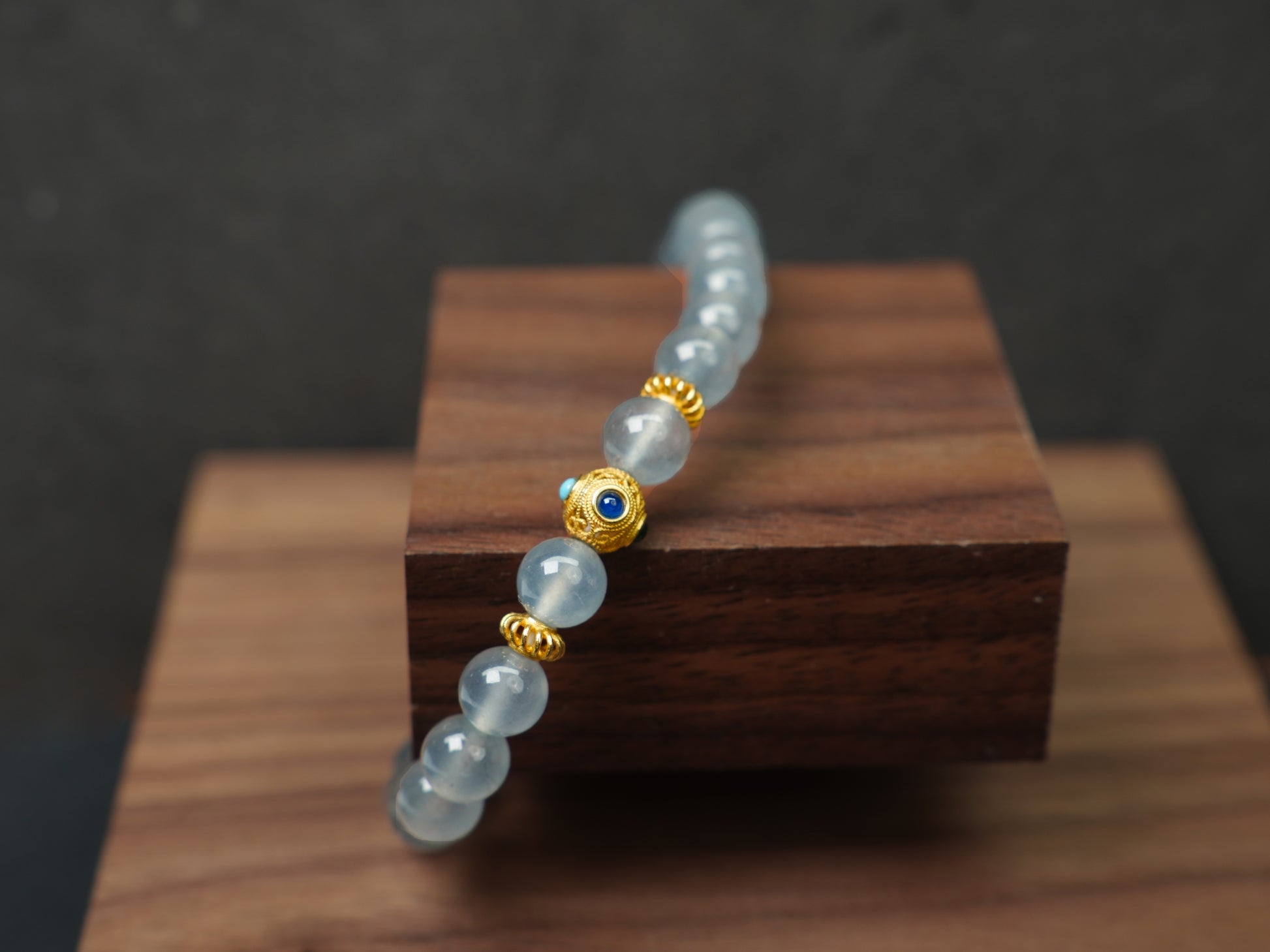 This bracelet combines icy jadeite beads with a hollow 18K gold center bead.