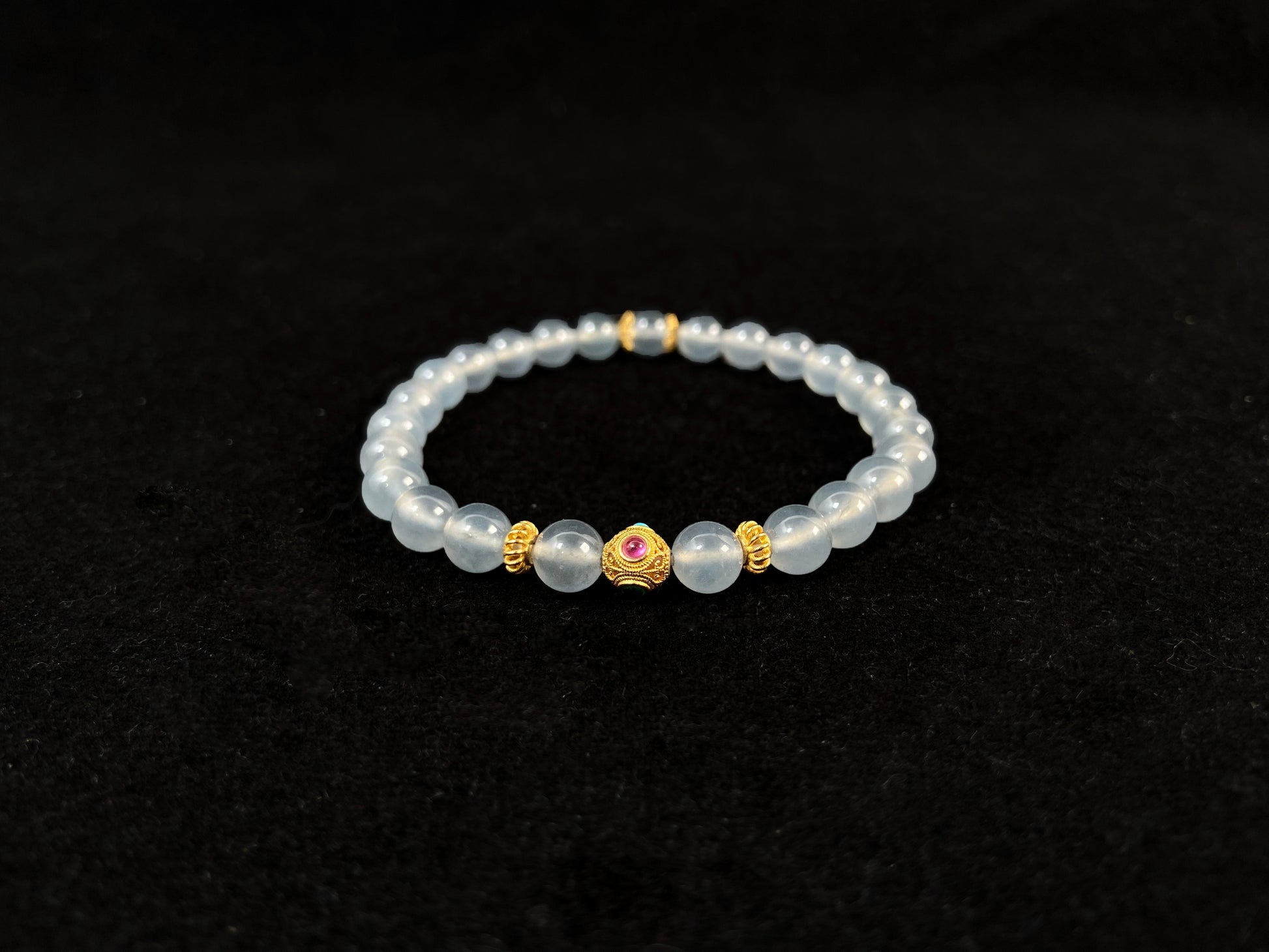 This bracelet combines icy jadeite beads with a hollow 18K gold center bead.