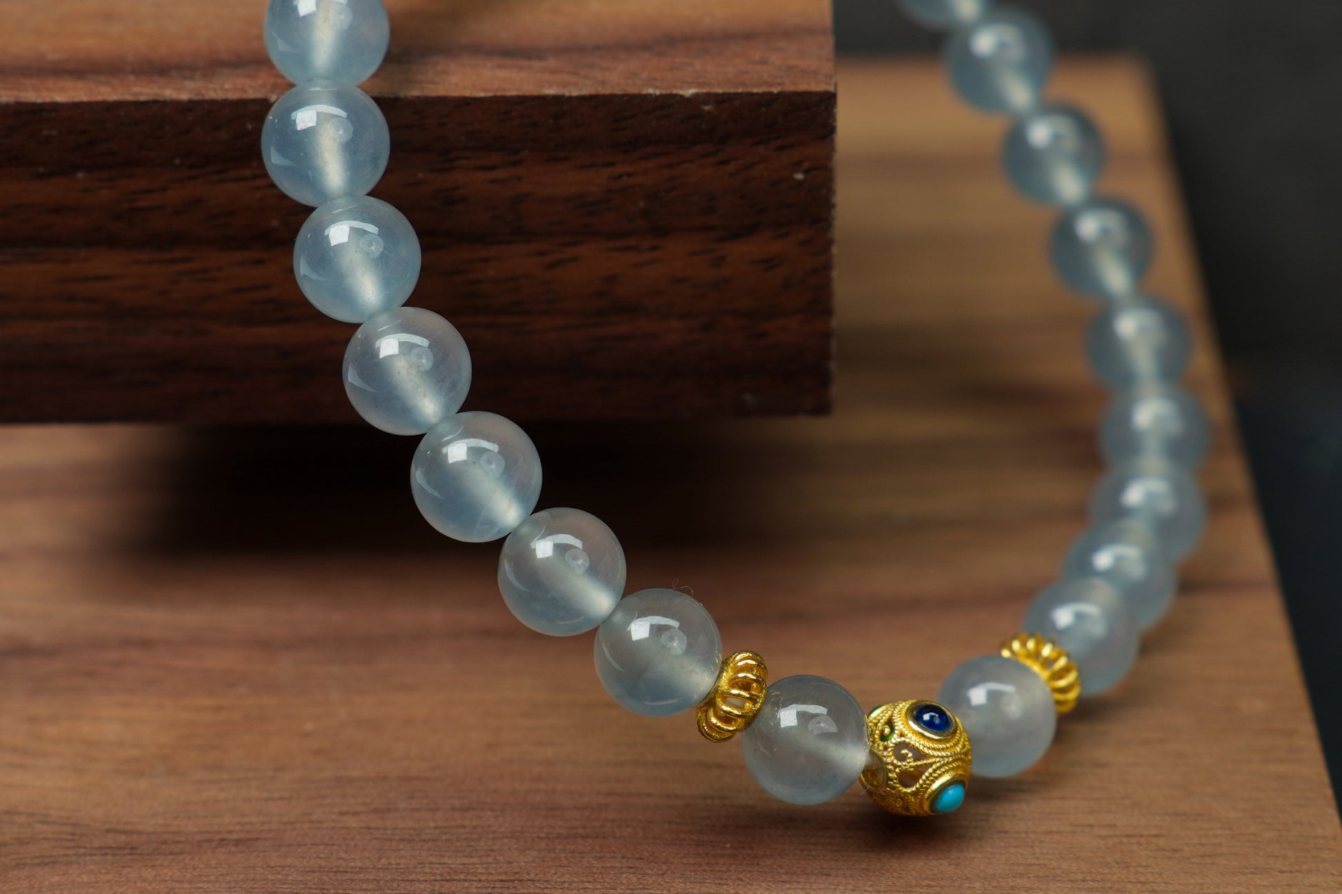 This bracelet combines icy jadeite beads with a hollow 18K gold center bead.