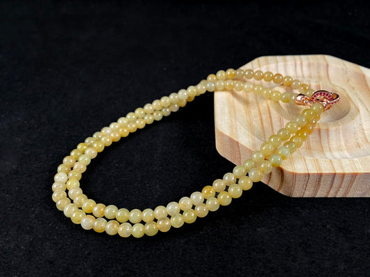 A semi transparent yellow jade bead strand connected by alloy end caps.
