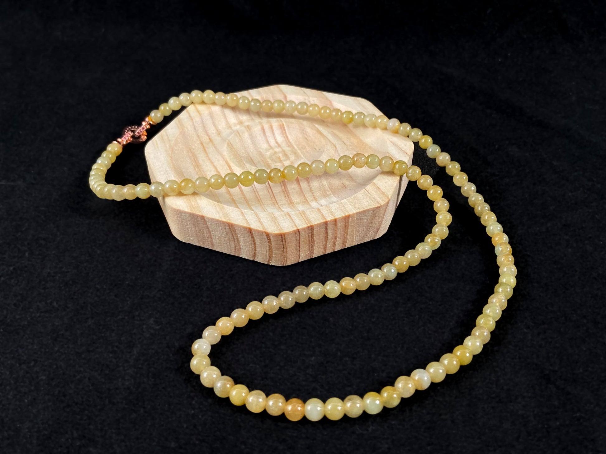 A semi transparent yellow jade bead strand connected by alloy end caps.
