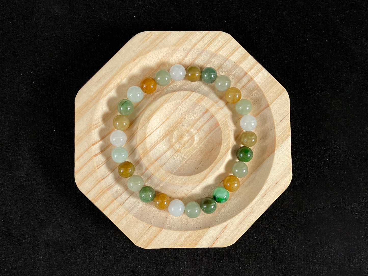 This jade bead strand features a natural palette of green, white, brown, olive, and yellow tones.