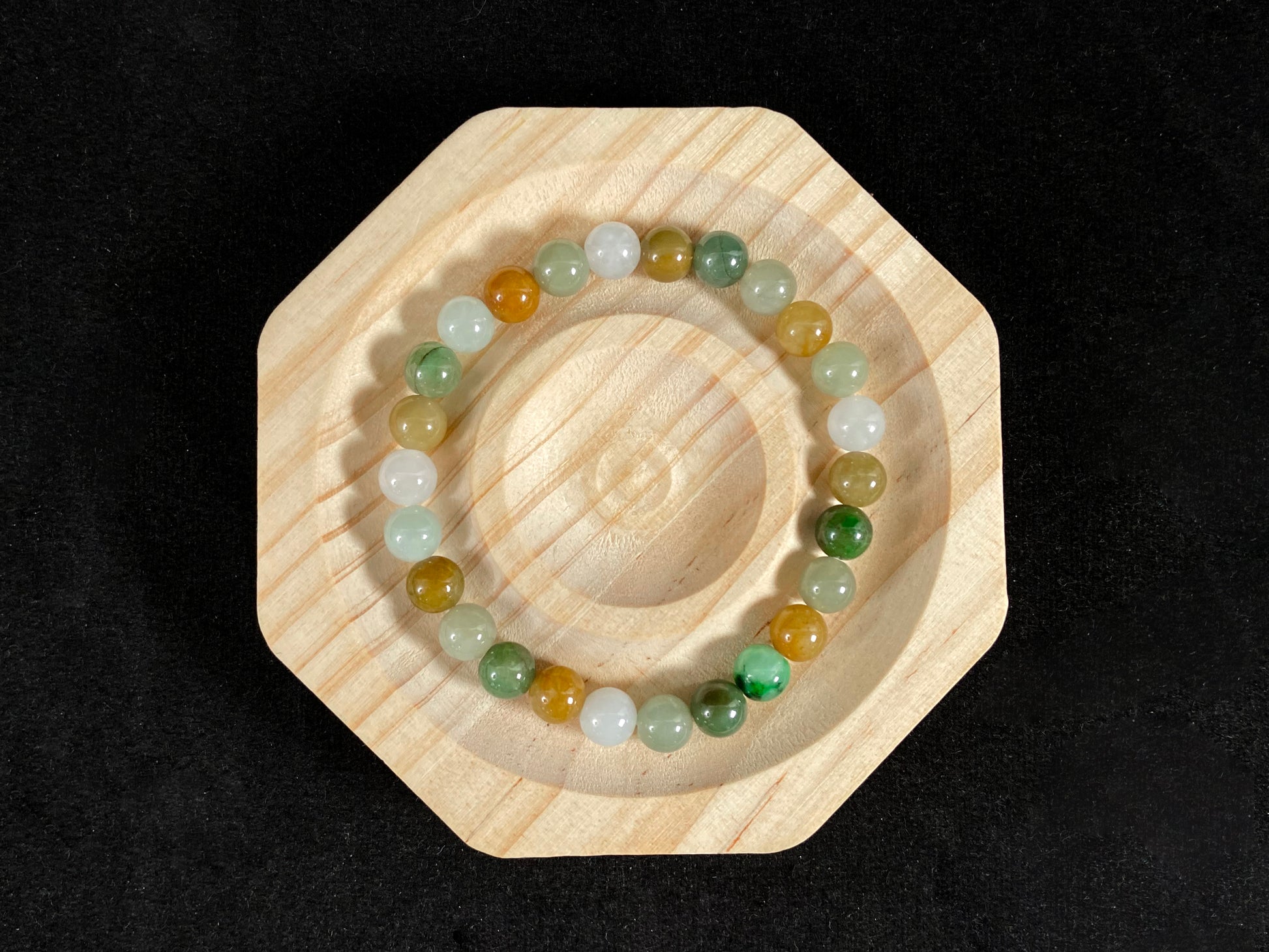 This jade bead strand features a natural palette of green, white, brown, olive, and yellow tones.