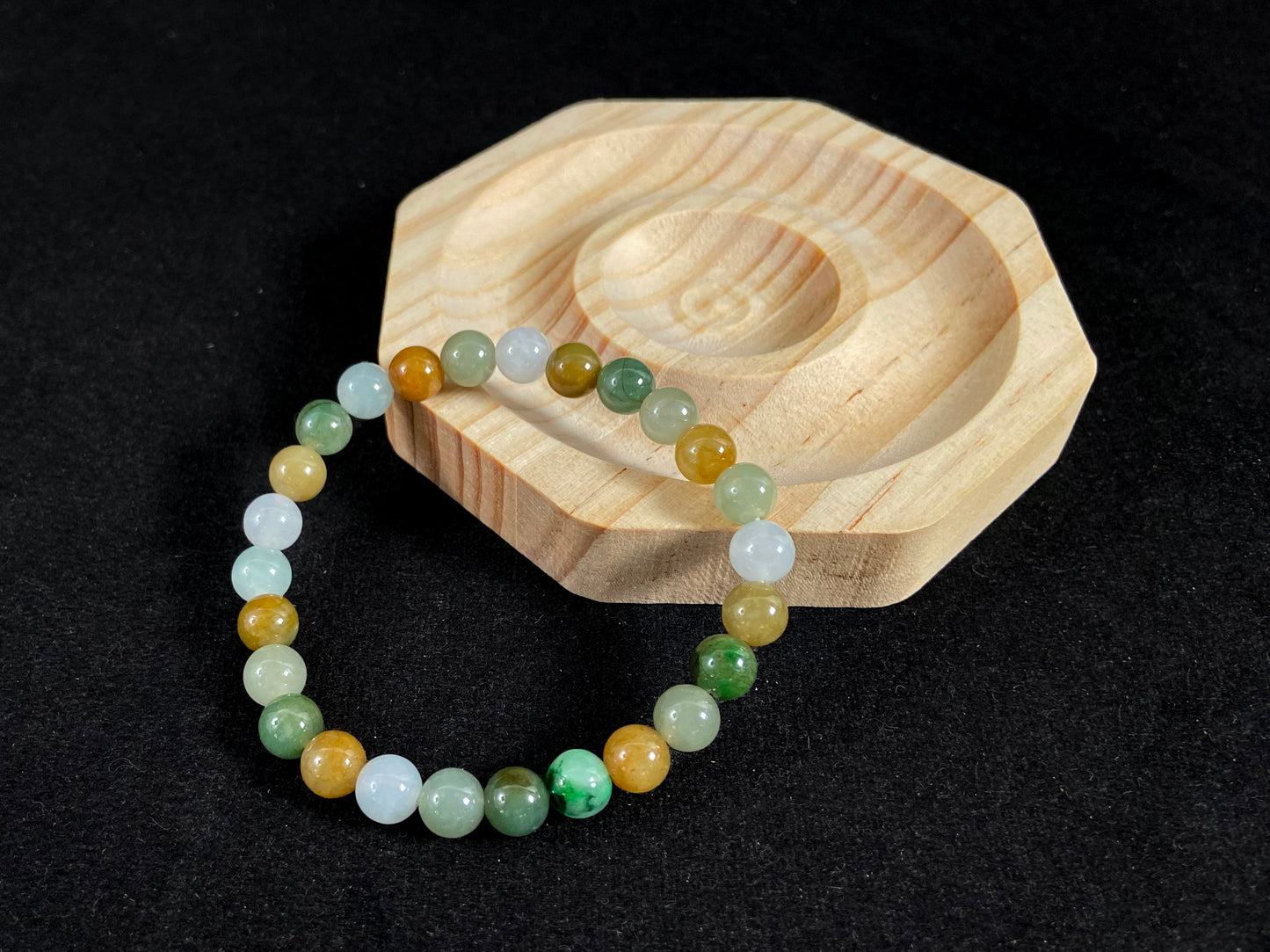 This jade bead strand features a natural palette of green, white, brown, olive, and yellow tones.