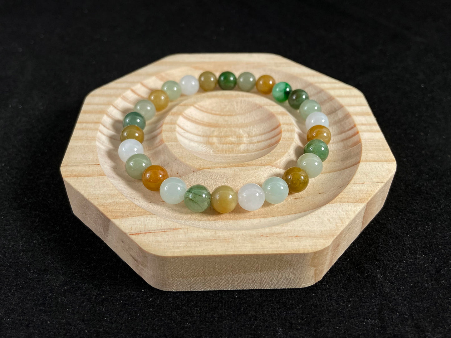 This jade bead strand features a natural palette of green, white, brown, olive, and yellow tones.