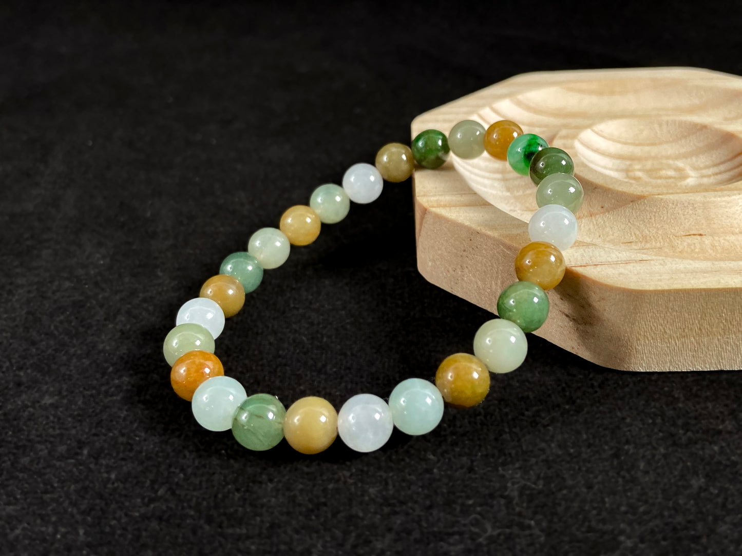 This jade bead strand features a natural palette of green, white, brown, olive, and yellow tones.