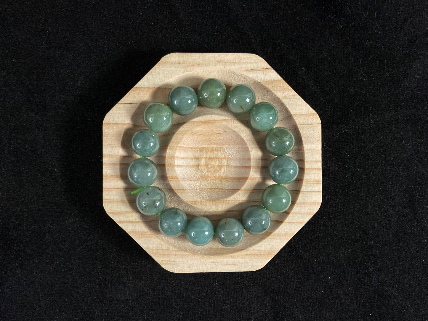 This jadeite bead strand features uniformly sized beads with a green base, accented by gold on some beads.