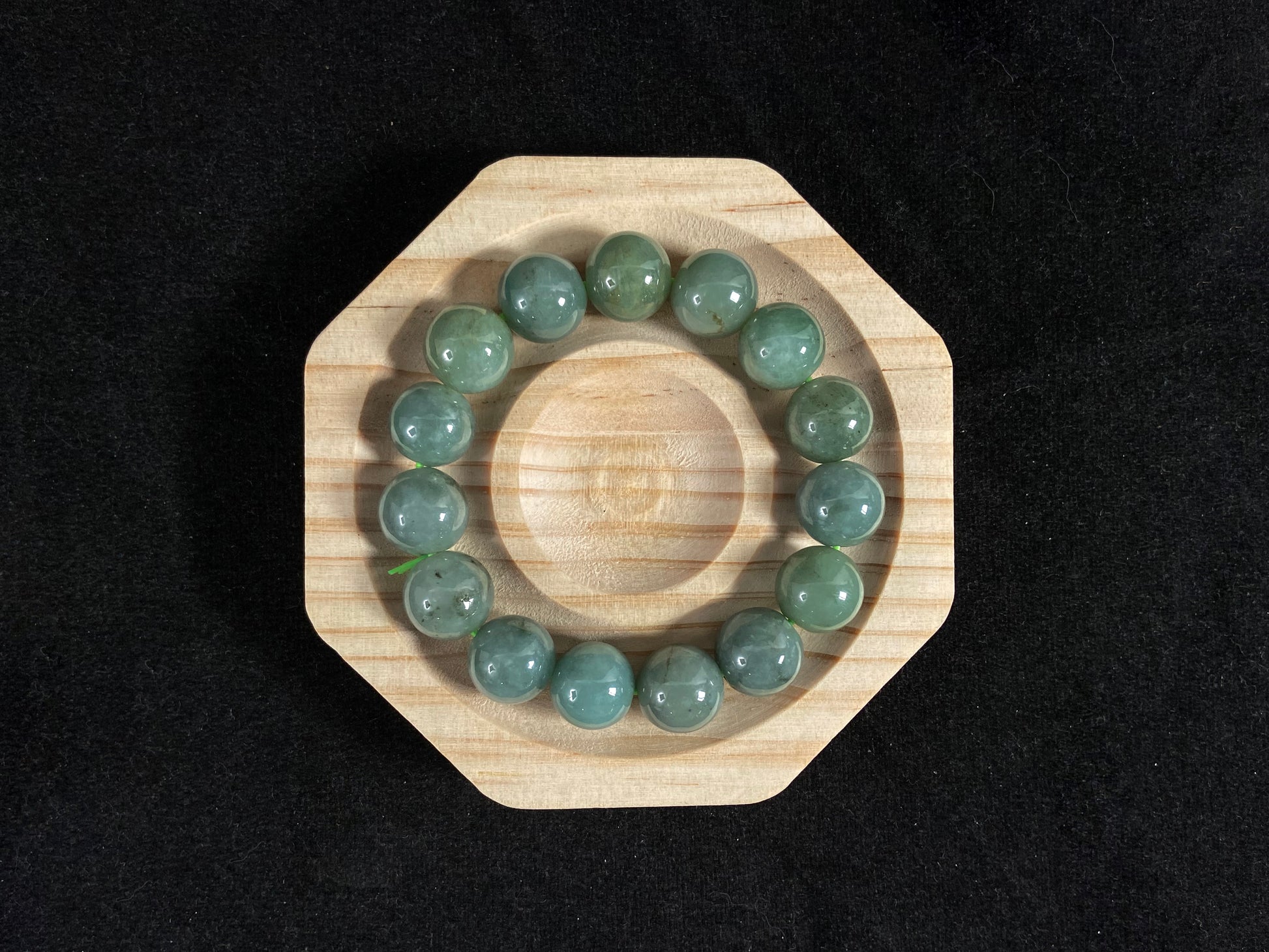 This jadeite bead strand features uniformly sized beads with a green base, accented by gold on some beads.