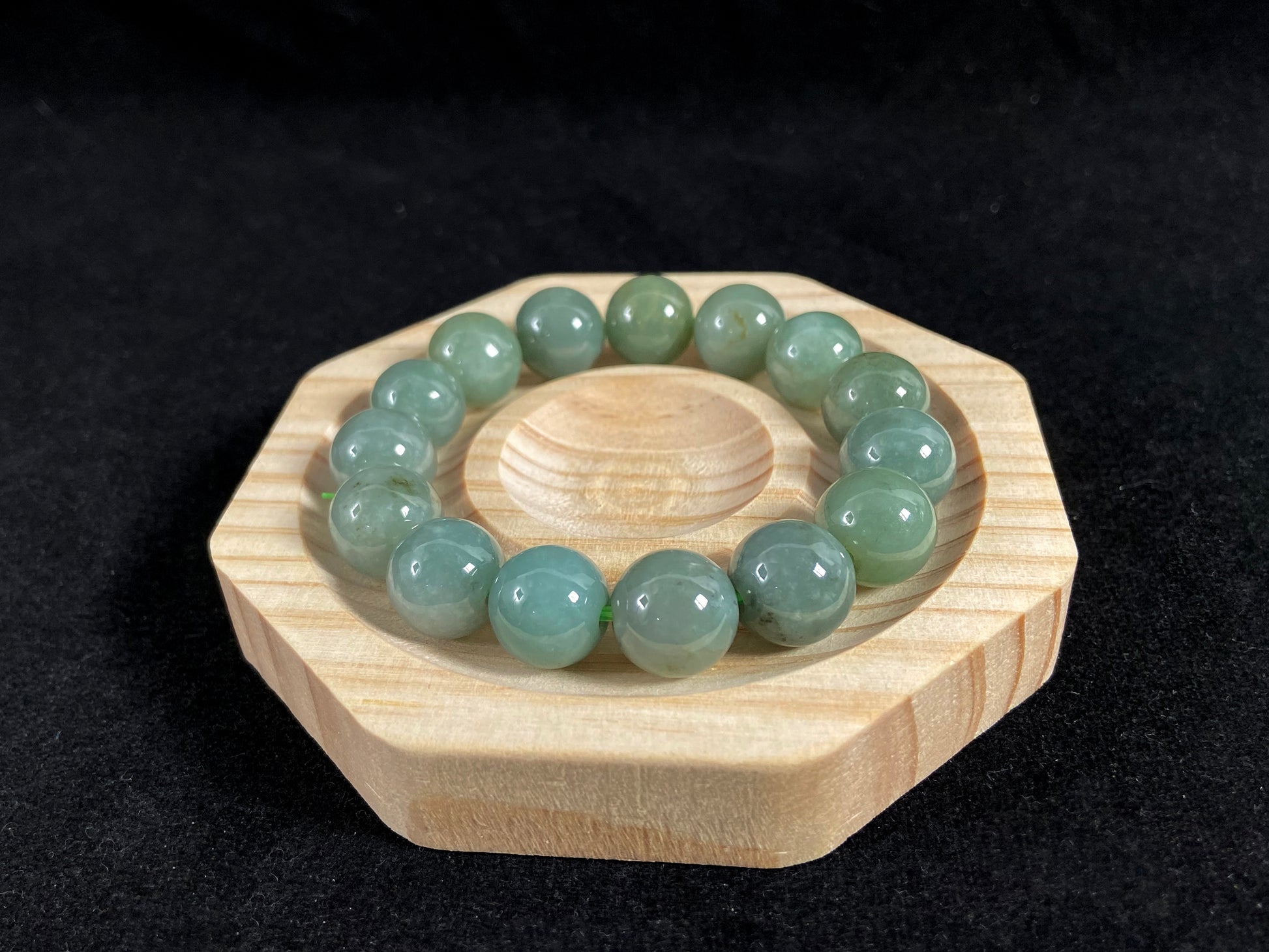 This jadeite bead strand features uniformly sized beads with a green base, accented by gold on some beads.