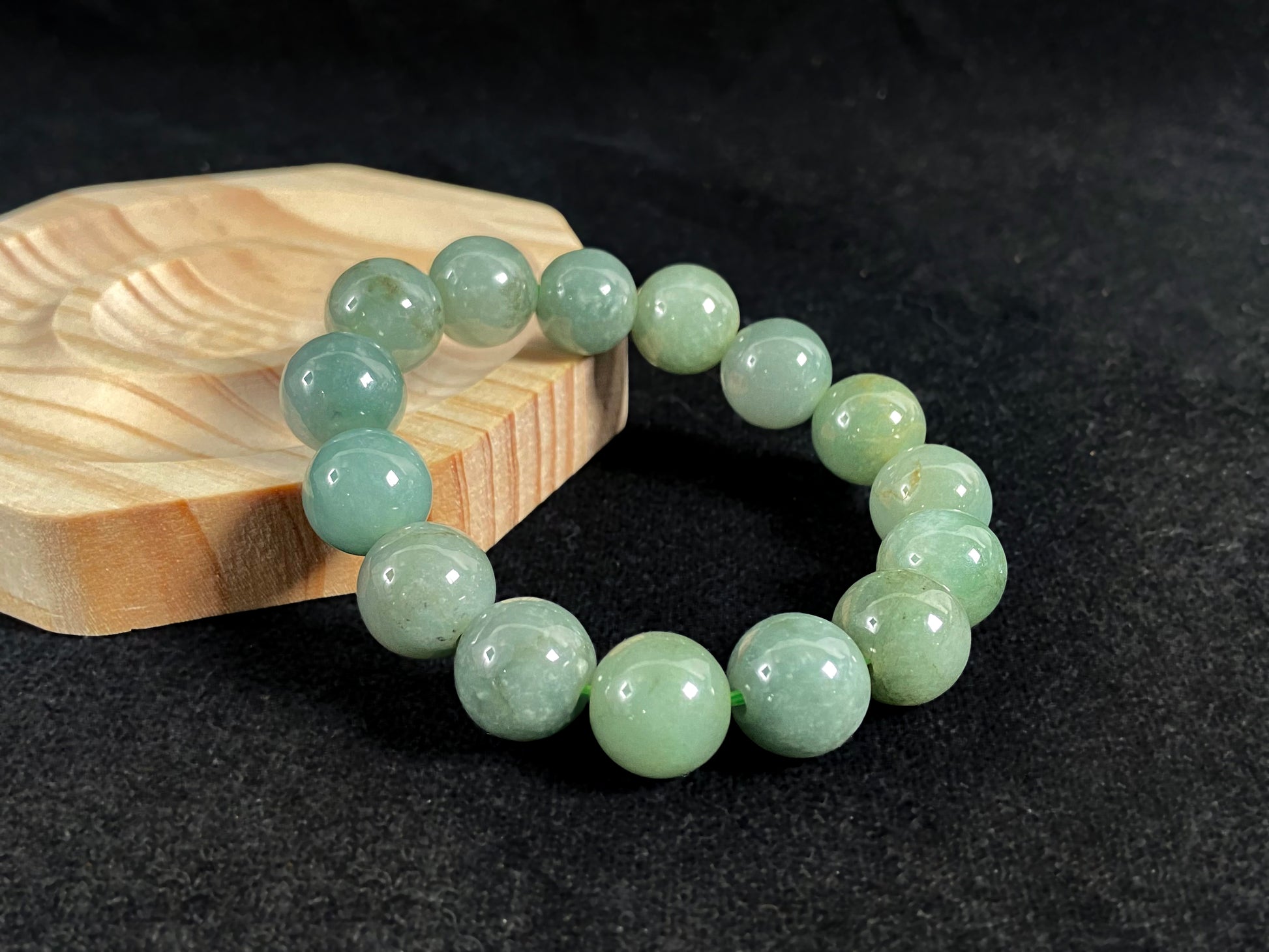 This jadeite bead strand features uniformly sized beads with a green base, accented by gold on some beads.