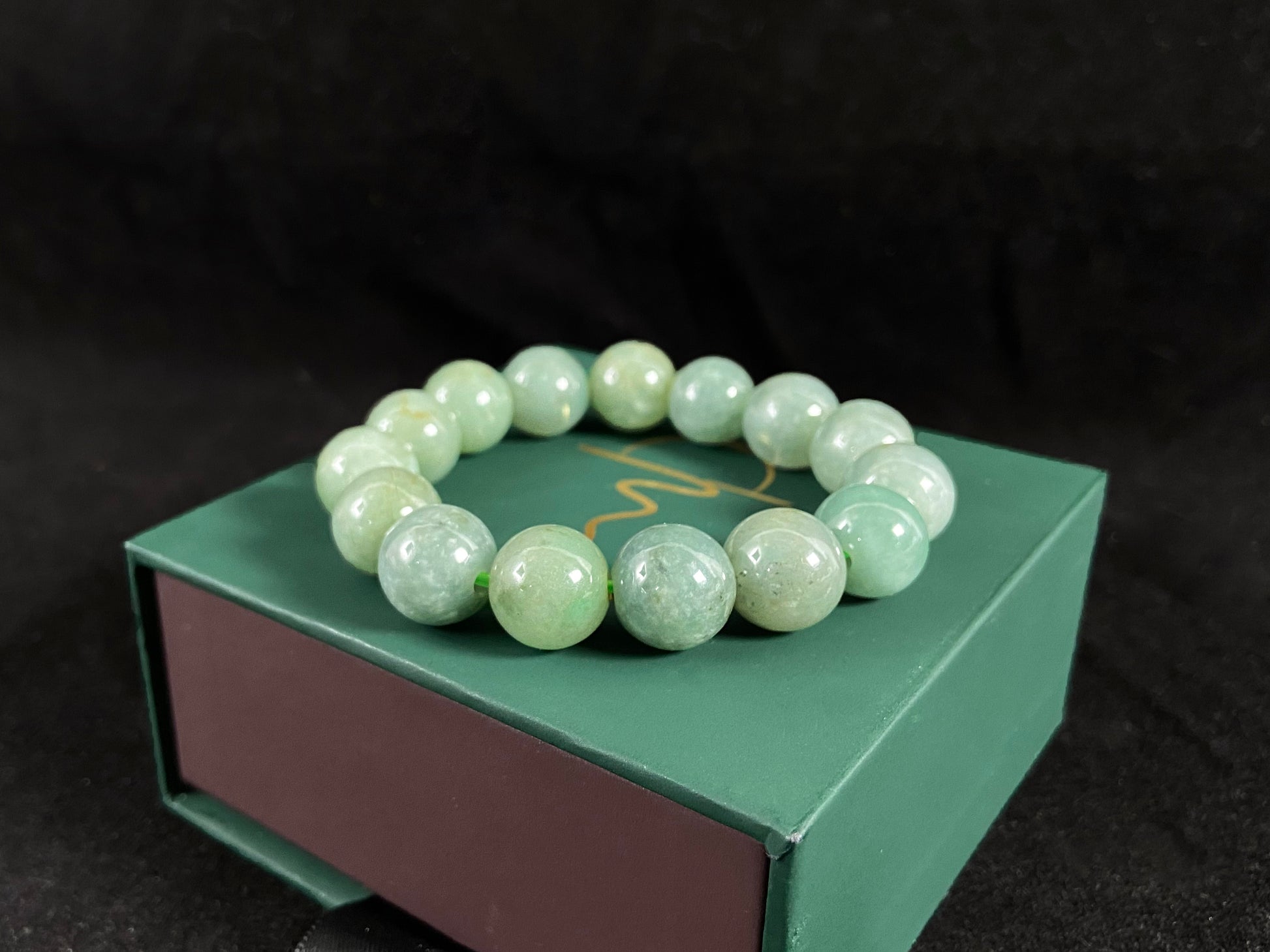 This jadeite bead strand features uniformly sized beads with a green base, accented by gold on some beads.