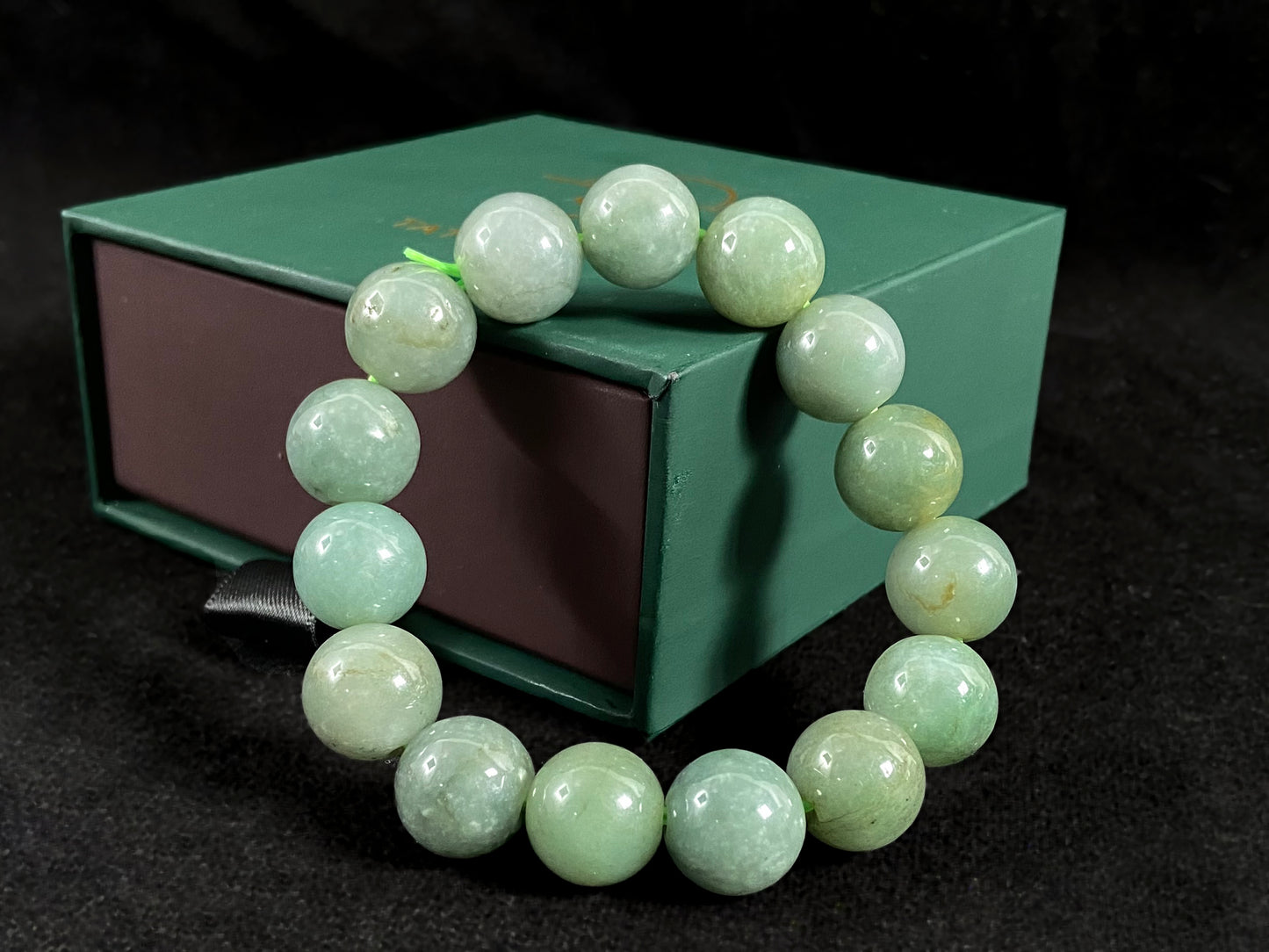 This jadeite bead strand features uniformly sized beads with a green base, accented by gold on some beads.
