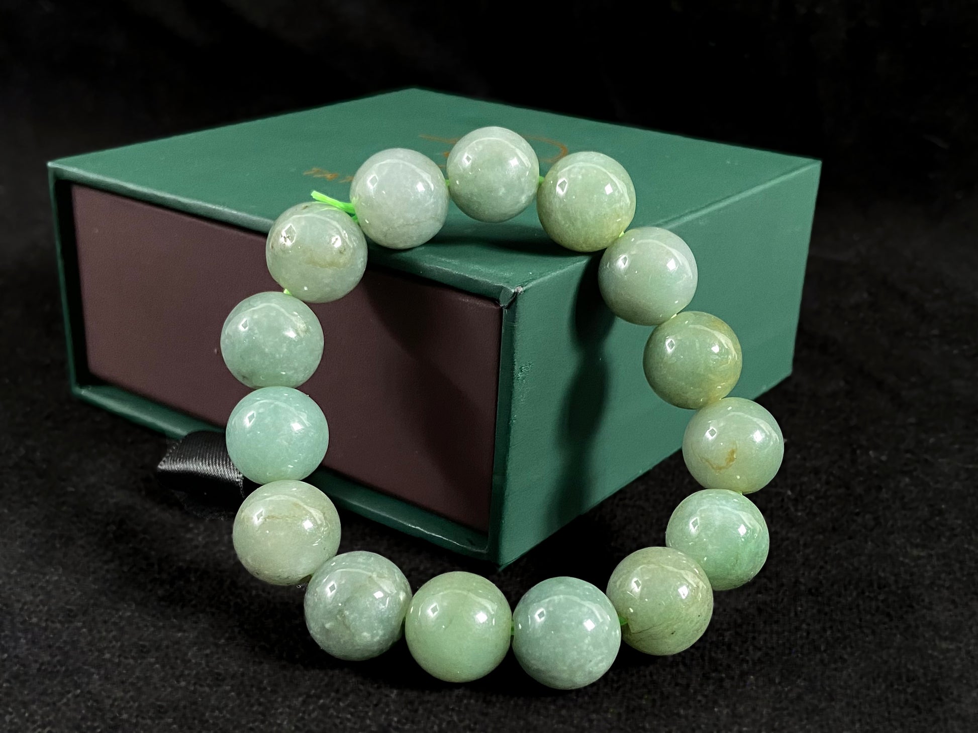 This jadeite bead strand features uniformly sized beads with a green base, accented by gold on some beads.