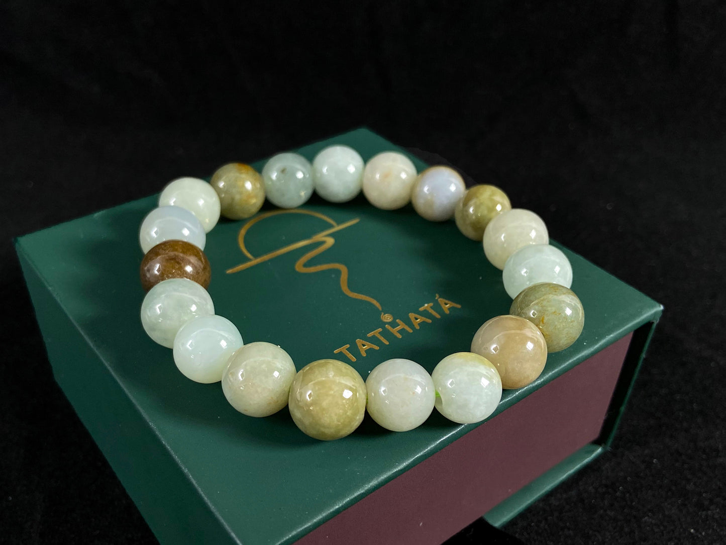 This jade bead strand features a palette of earthy browns, mossy greens, and creamy white.