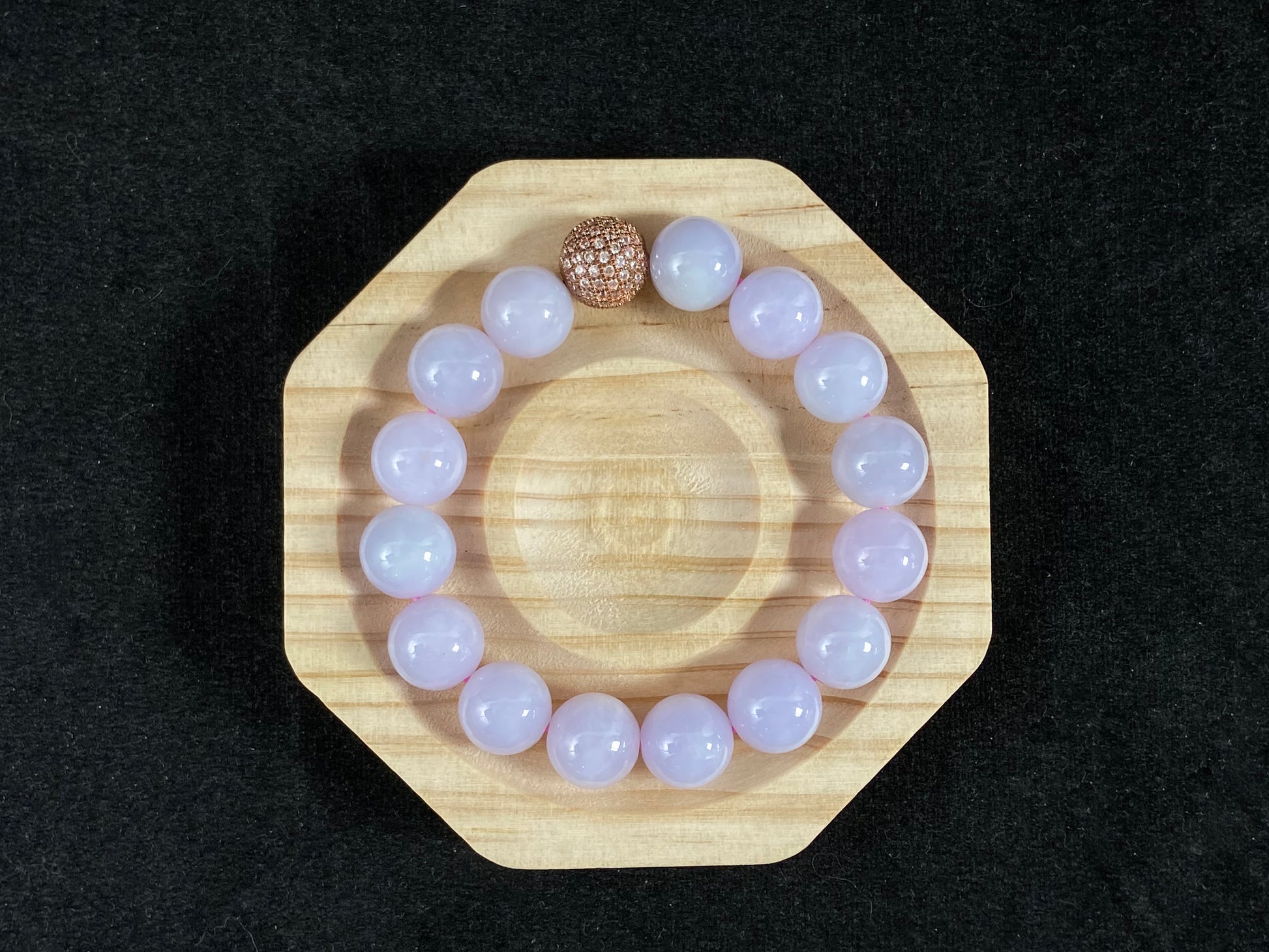 A lavender jade bead strand featuring a silver master bead encased in a gold web pattern.