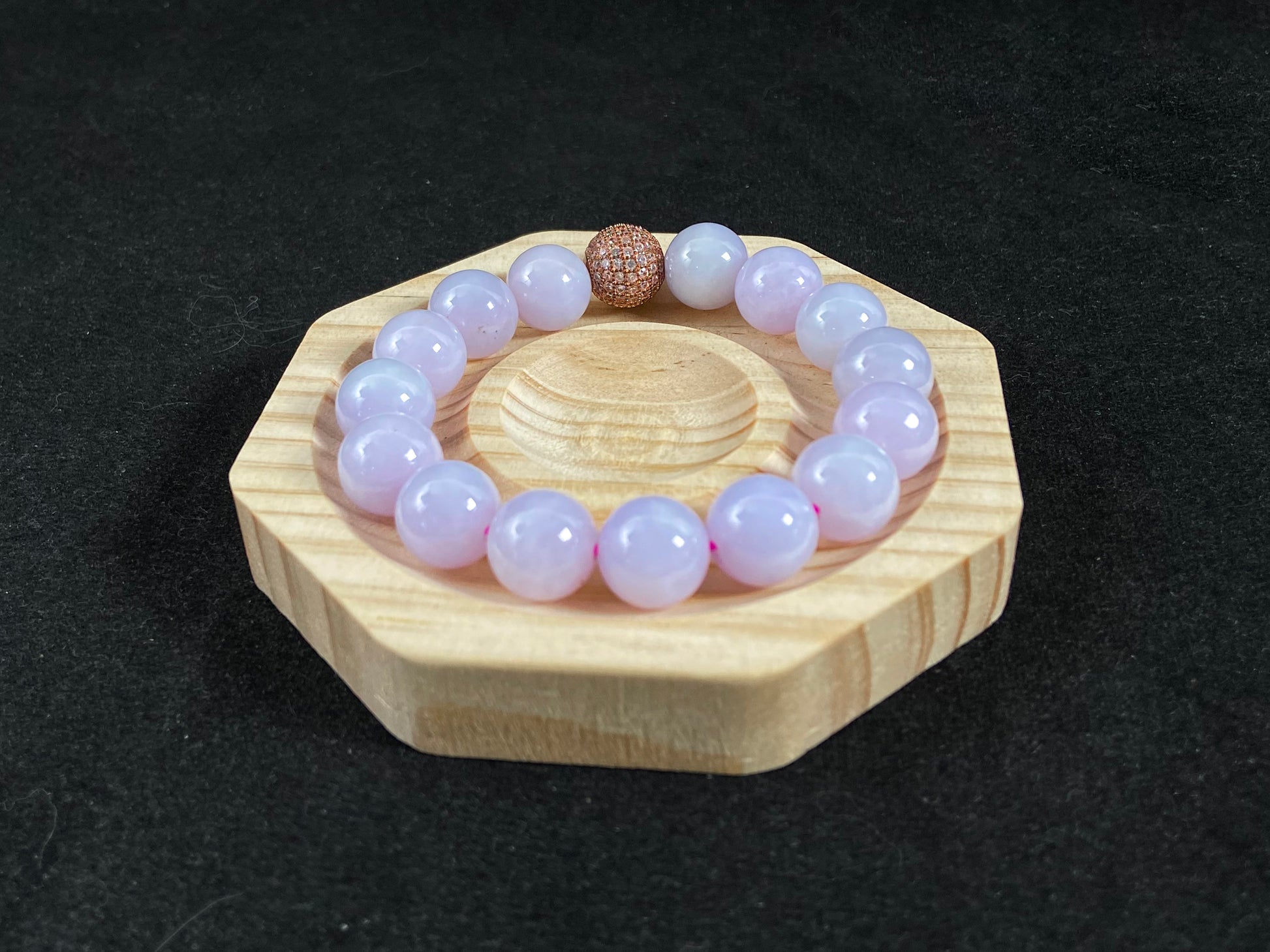 A lavender jade bead strand featuring a silver master bead encased in a gold web pattern.