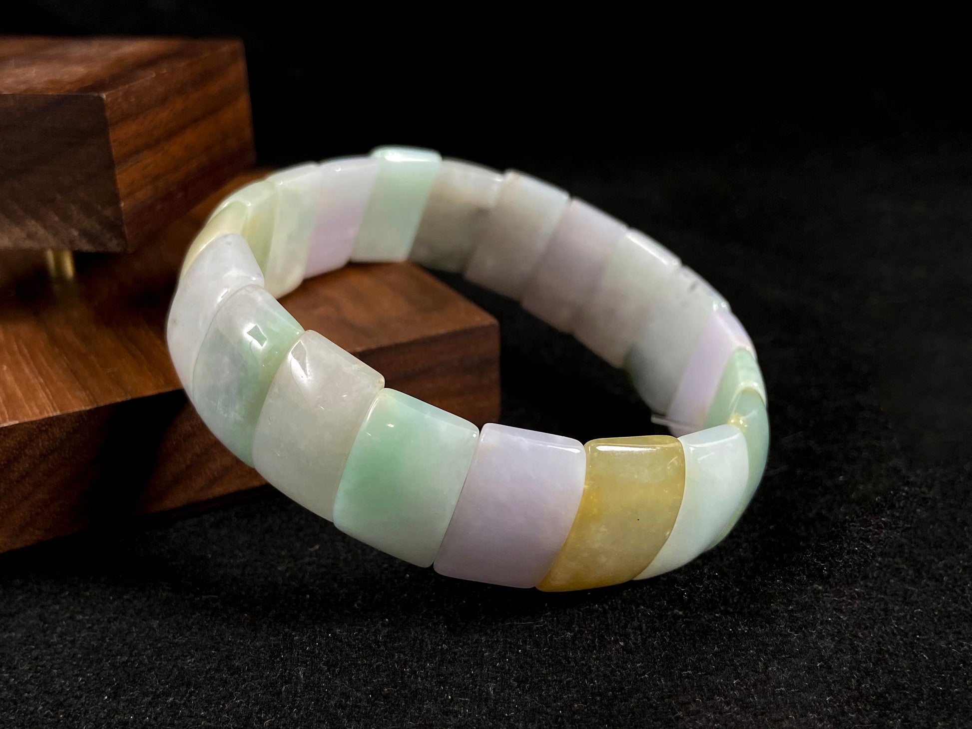 A rectangular jade bangle featuring an earthy palette of green, cream, purple and brown.